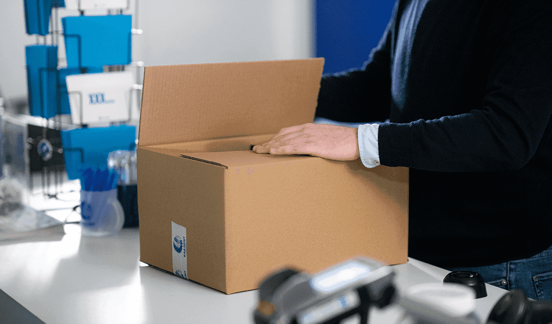 A retailer closing a cardboard box at a packing station
