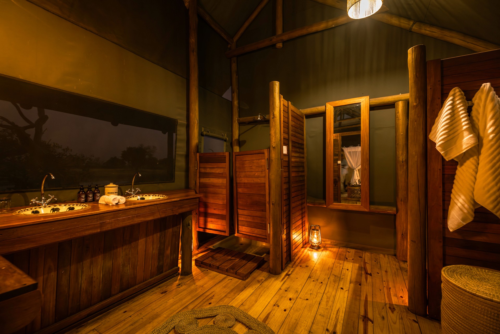 Kujwana Delta Ride, Okavango Delta Botswana. Riverside Suites på Kujwana Camp. Lyxigt ensuite badrum i mysigt upplyst sken som en del av Riverside Suites