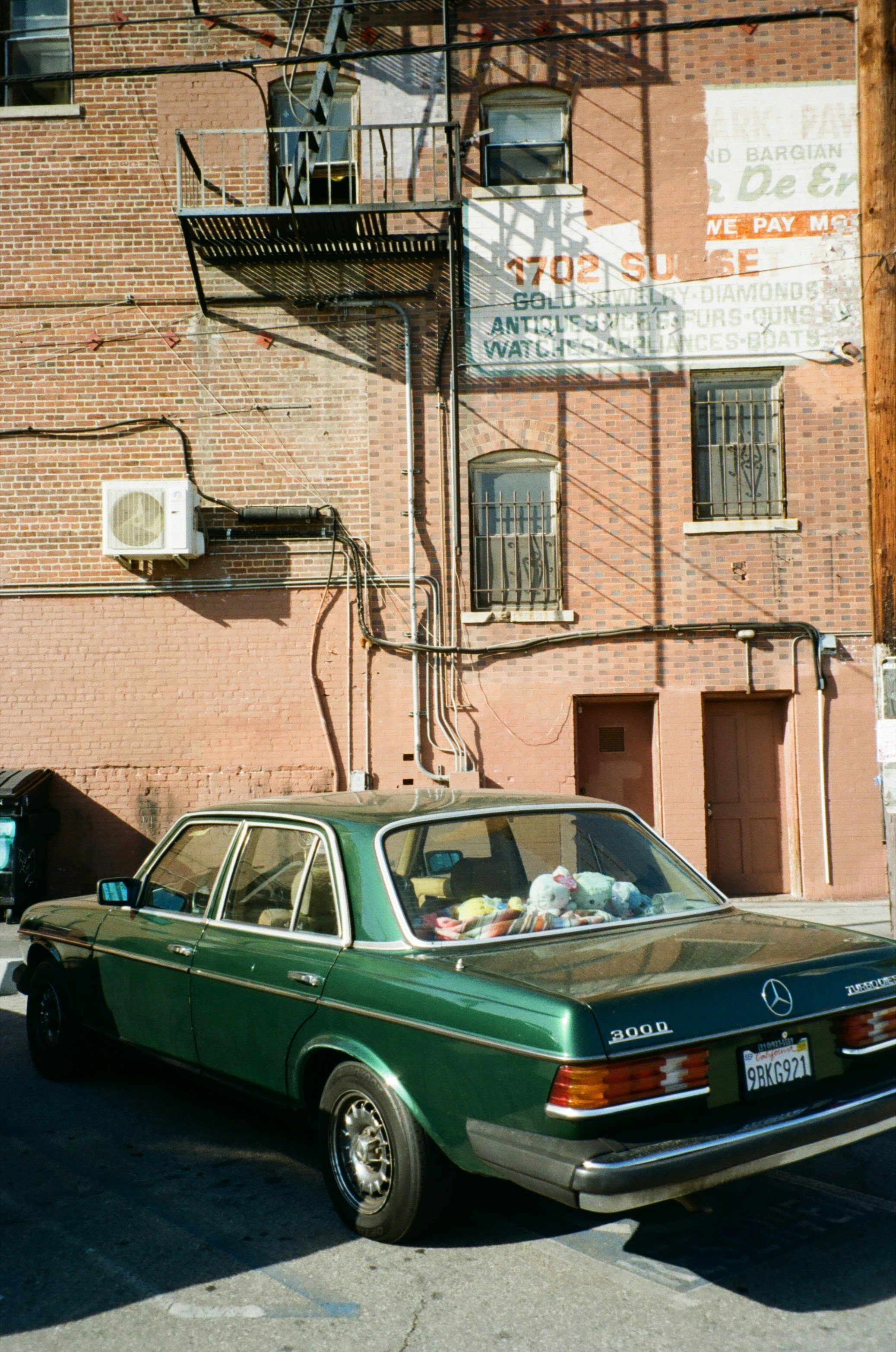Green mercedes parked against brick building