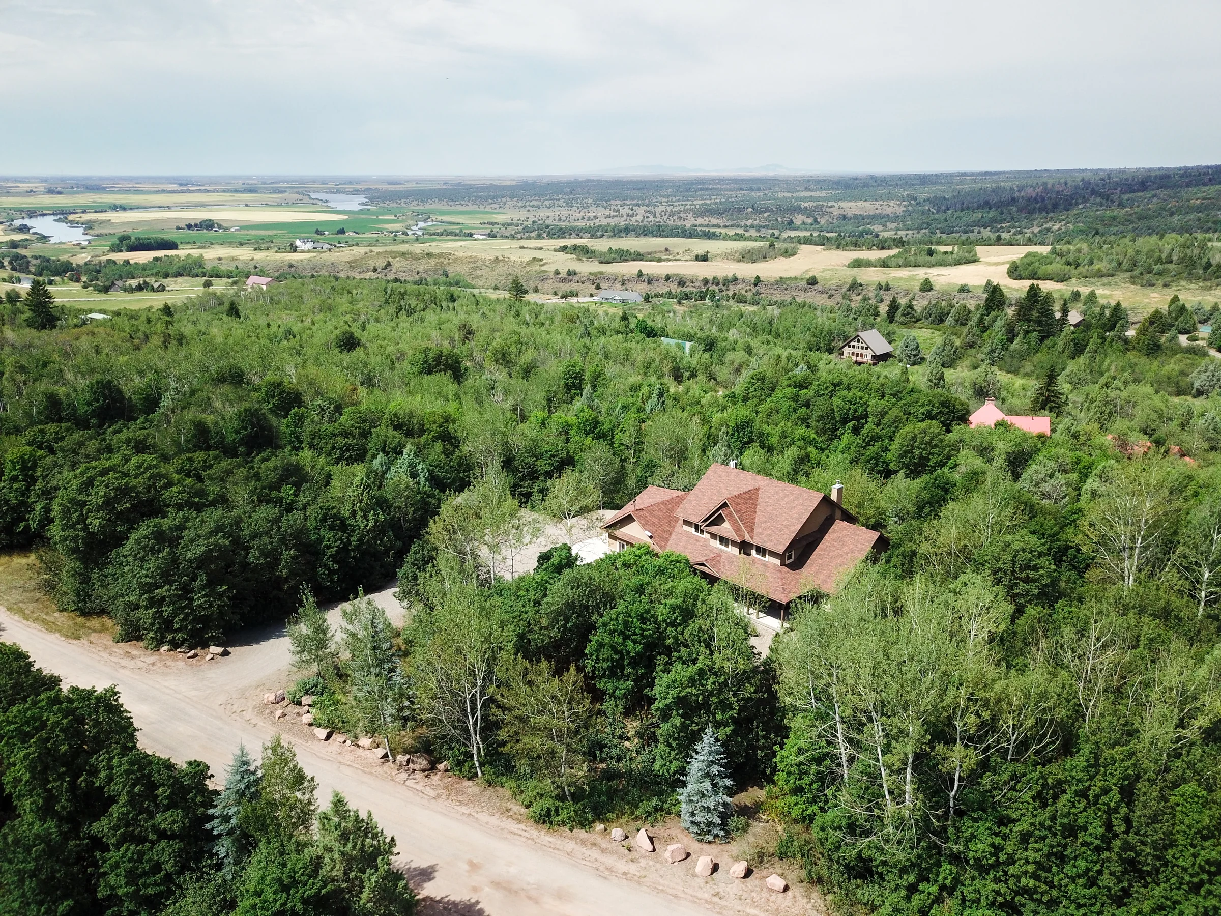 Aerial view of a home among trees with farmland beyond