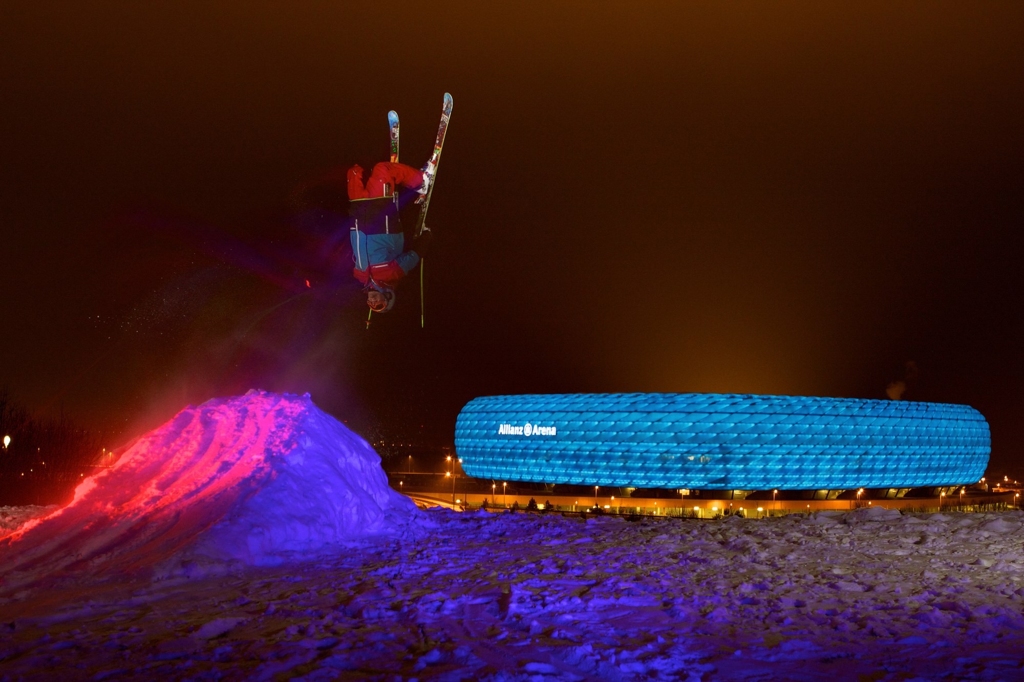 Night shoot: Tobi Deckert jumping under floodlights in front of an illuminated backdrop — productions like this became possible through the team's contacts in the ski industry