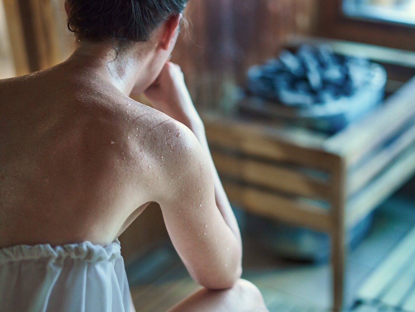 woman sweating in a sauna after deciding between sauna or steam room for weight loss