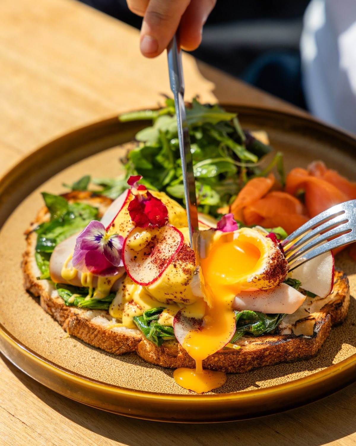 Close-up of gourmet eggs benedict with runny yolk at Dhoom, highlighting the restaurant’s vibrant plating, fresh ingredients, and immersive fine dining atmosphere.