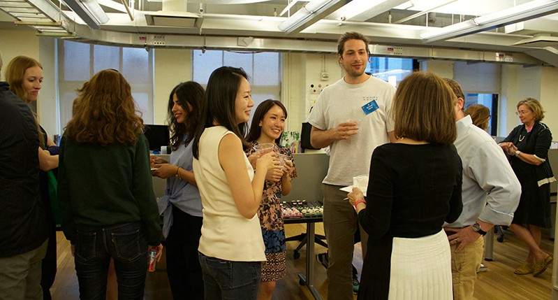 A photo of a group of people sitting in an office room and talking.