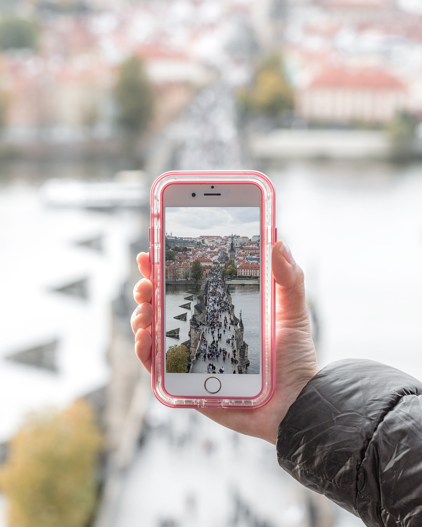 Smartphone screen displays a bright cityscape view across a wide river under soft daylight.