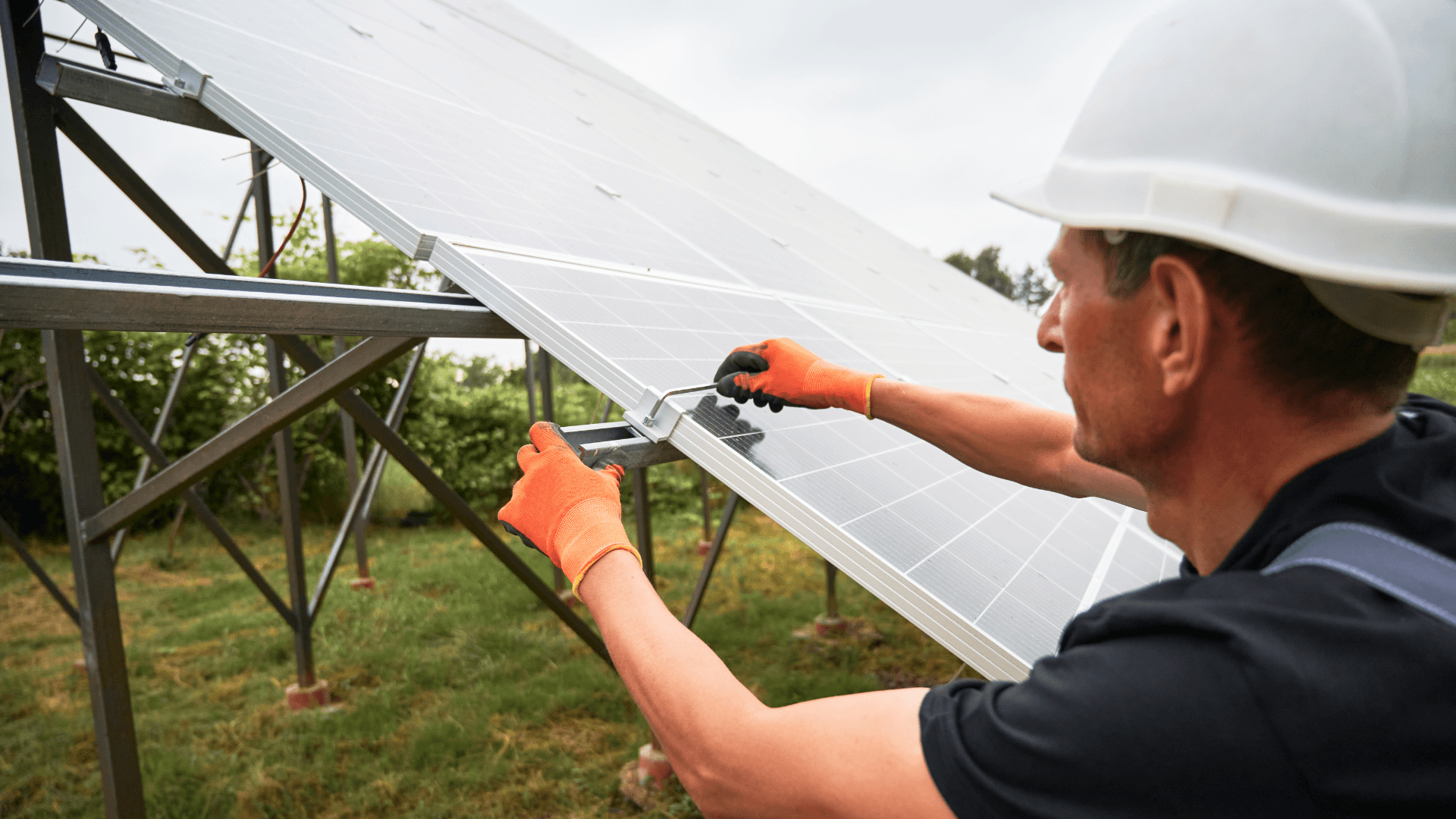 Ein Arbeiter mit Schutzhelm justiert mit Werkzeugen Ausrüstung an einer Konstruktion und konzentriert sich dabei auf die Aufgabe in einer Außenumgebung.
