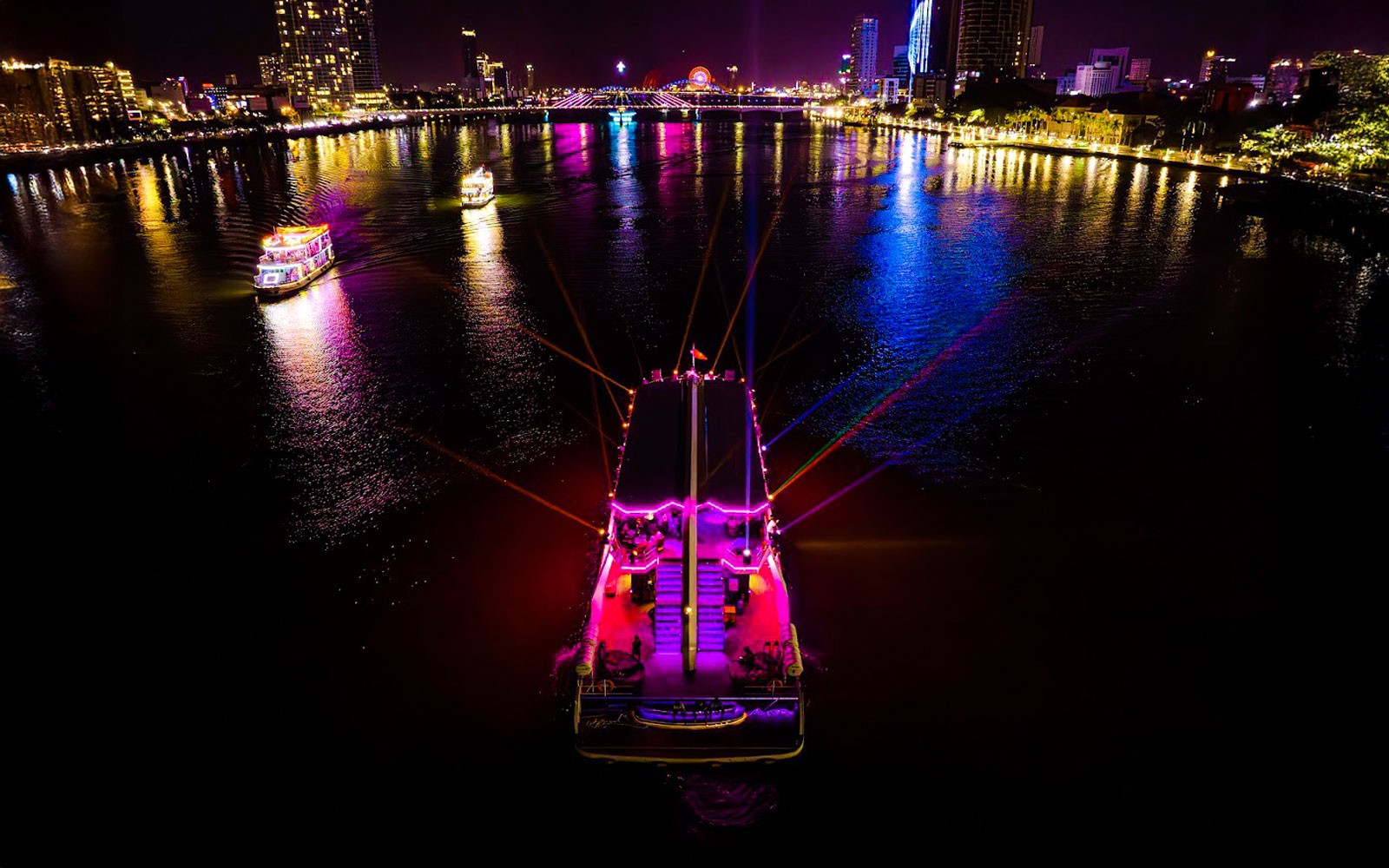 Da Nang Poseidon cruise at night with vibrant city lights reflecting on the river.