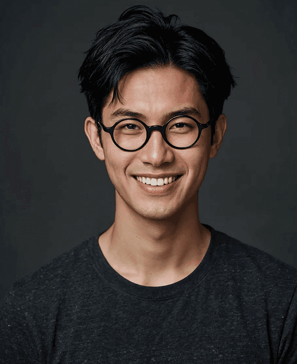 A smiling young man wearing glasses poses for the camera, exuding confidence and friendliness.