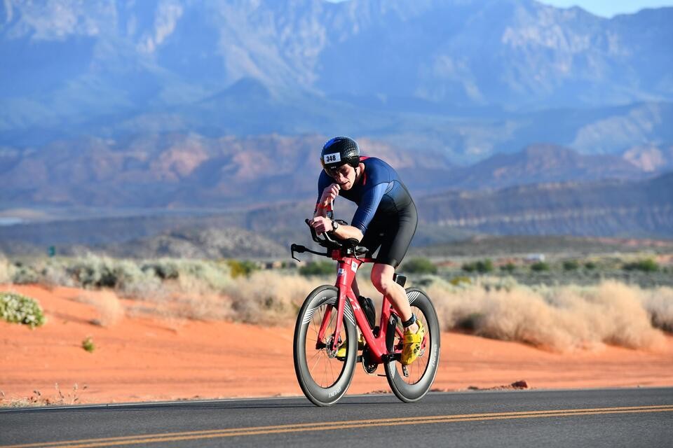 Triathlete riding a red tri bike through Utah desert
