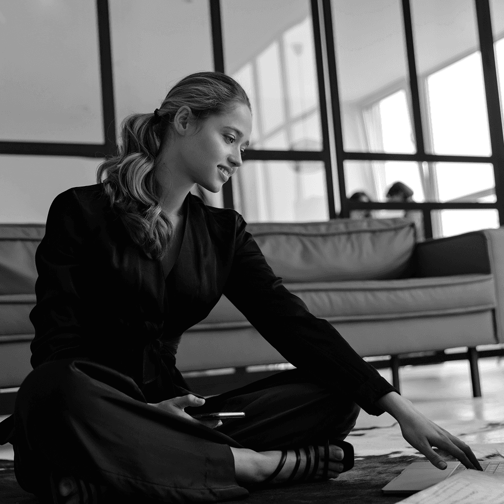 A calm lady wearing brown overcoat with a white top looking towards camera