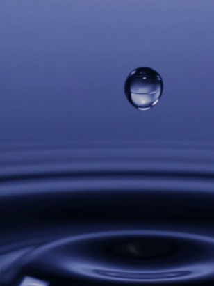 Female scientist wearing a white coat and gloves examines a sample slide in a modern laboratory setting.