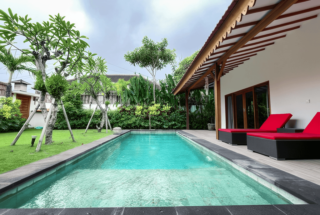 Private lap pool with red sun loungers in a lush garden. Top real estate agent for Canggu villa investments.