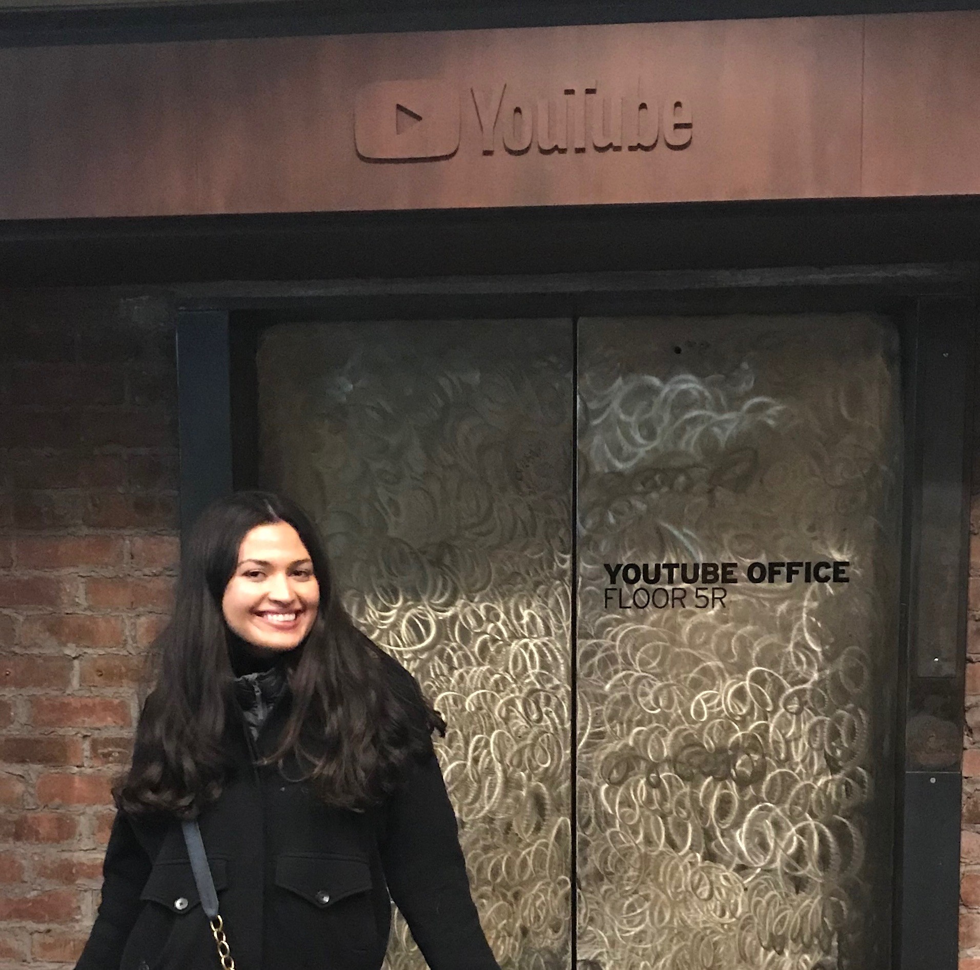 woman standing in front of an elevator that says "YouTube"