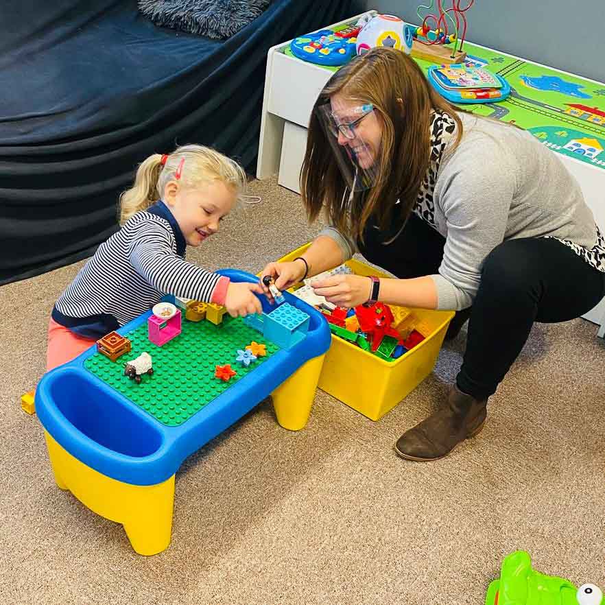 A child and Horizon Hub team member are playing with Duplo in a classroom