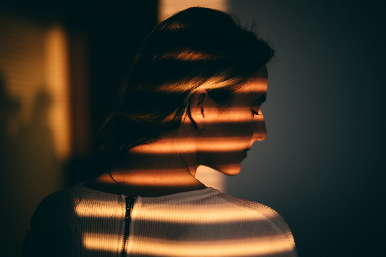 Strong daylight through window blinds falling across a face and shoulder