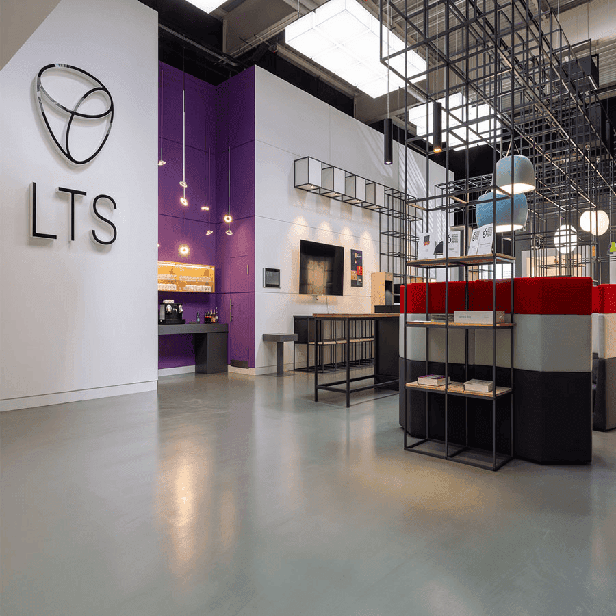 Modern glass and steel building with warm wooden ceilings, surrounded by lush greenery, blending contemporary architecture with nature.