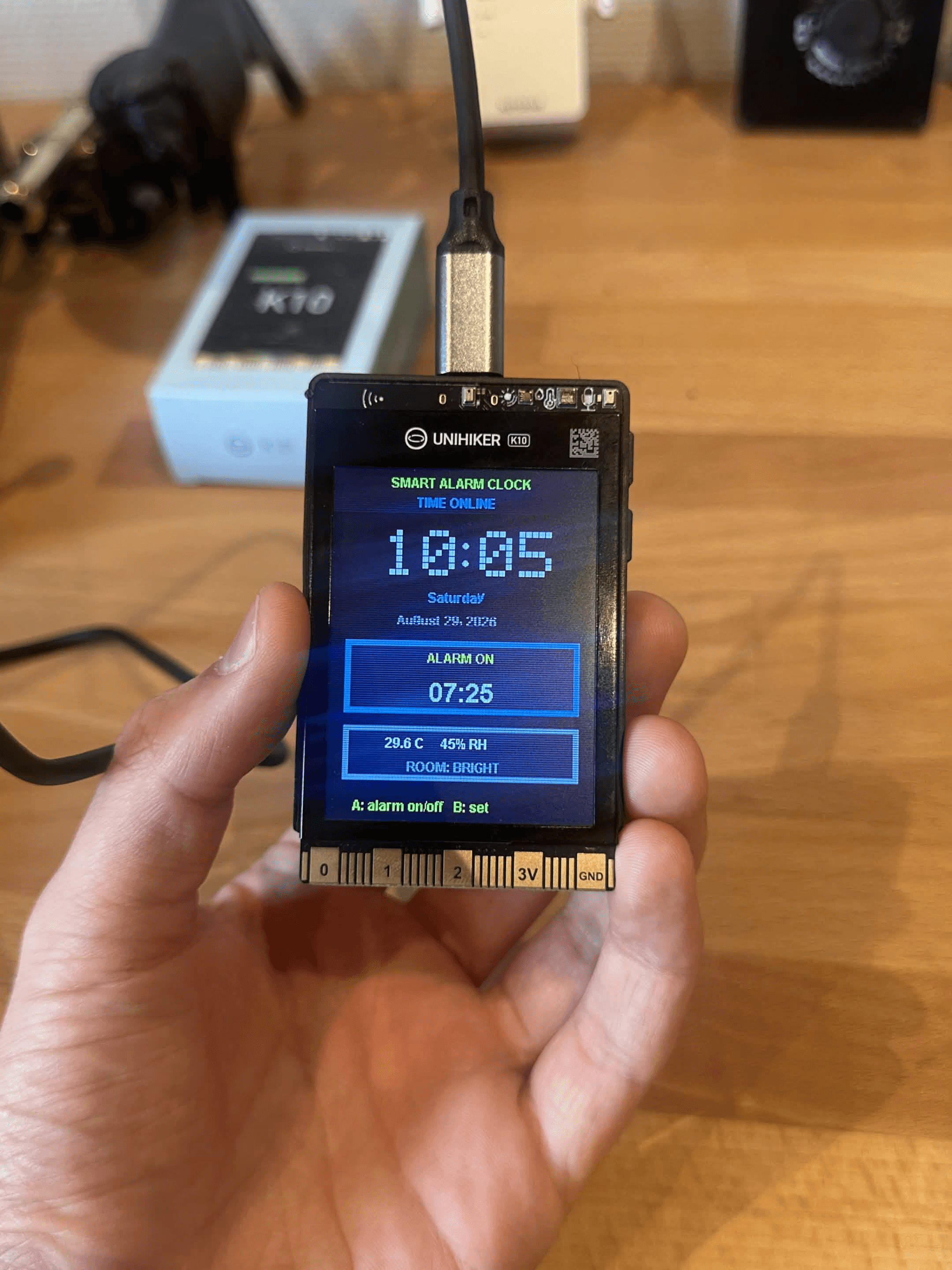 UNIHIKER K10 smart alarm clock displaying the current time and alarm setting.