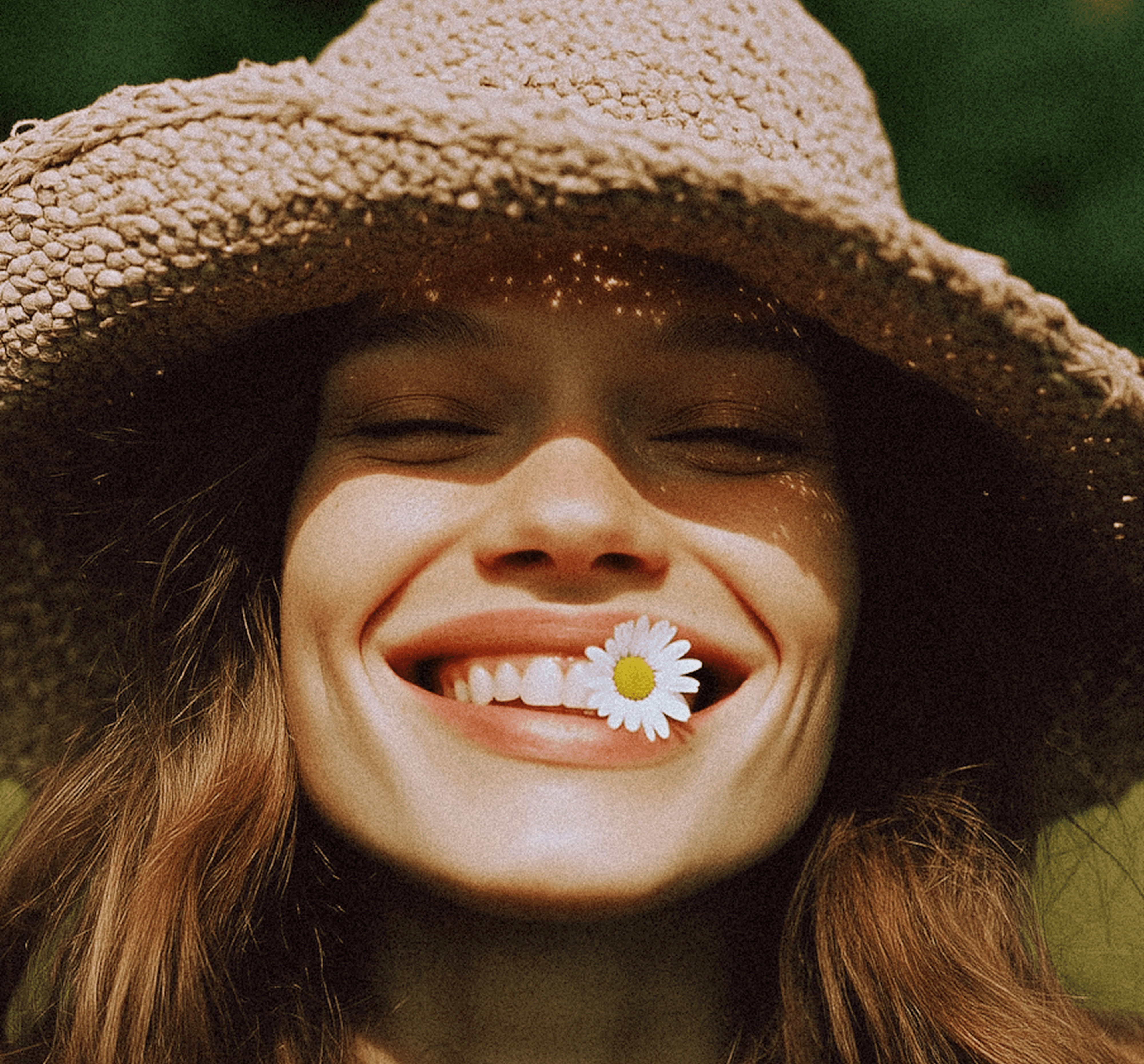 Smiling person in straw hat with daisy