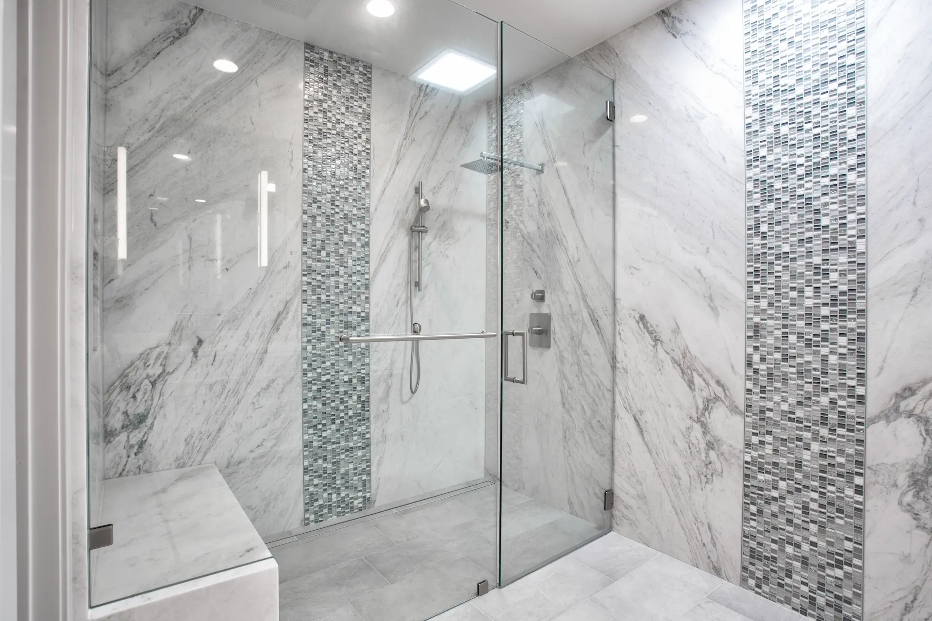 Elegant shower with glass door, marble tiles, and mosaic accents in Costa Mesa Remodel. Photo by Chris Darnall.