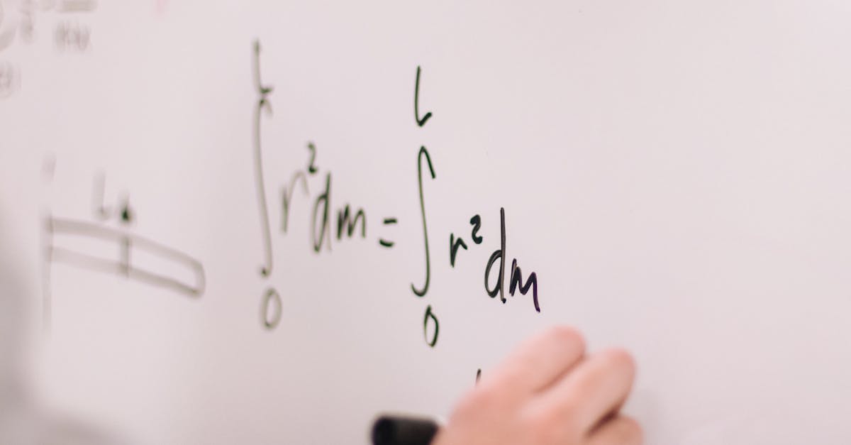 Person writing math equations on a whiteboard, focusing on integrals and formulas.
