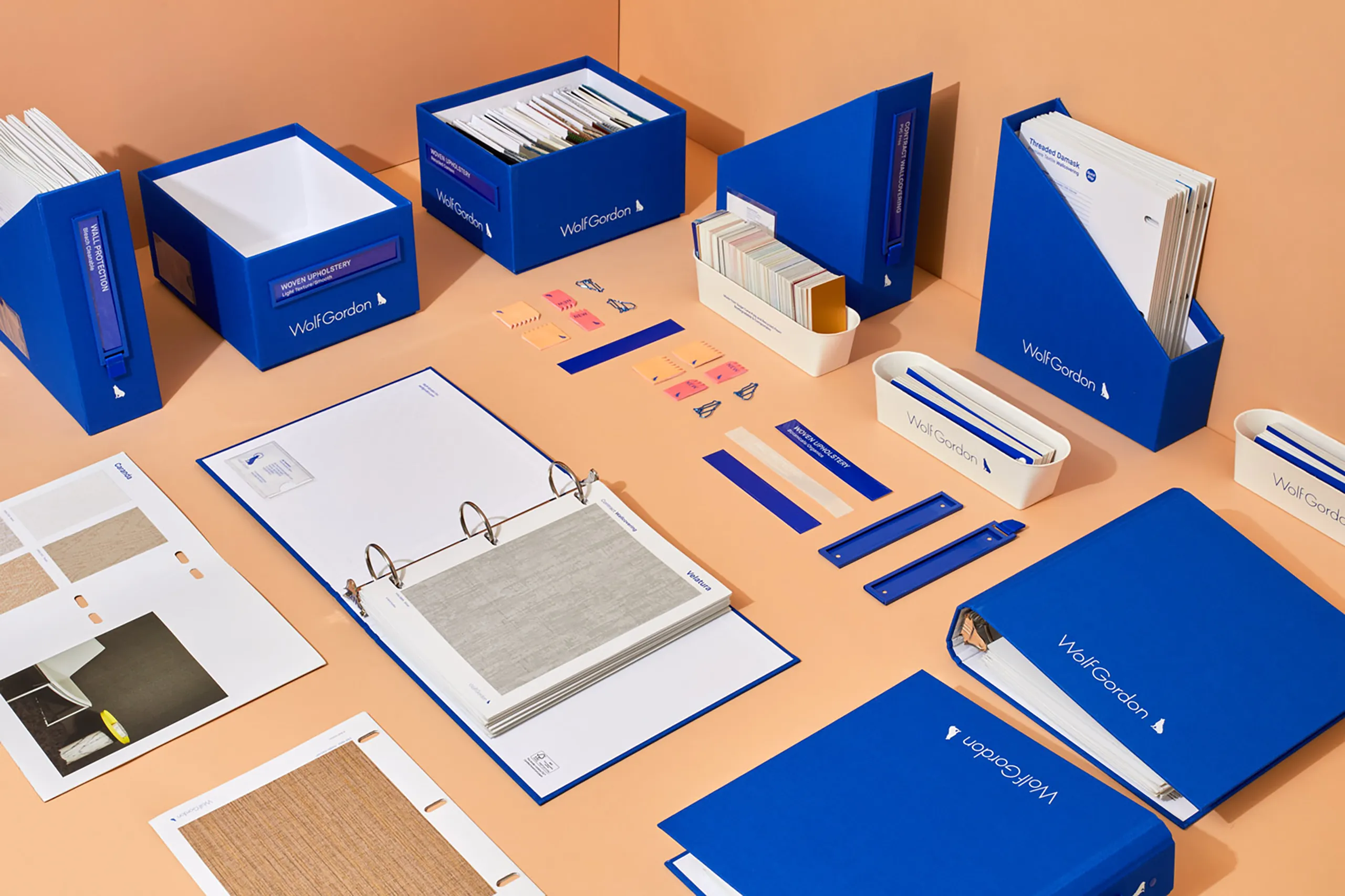 Wolf-Gordon material sample system with binders, swatches, organizers, labels, and accessories arranged on orange