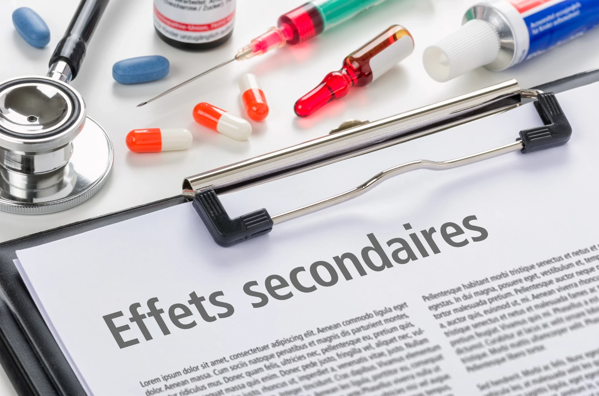Un presse-papiers contenant des documents médicaux, des seringues et du matériel de laboratoire disposés sur une table.