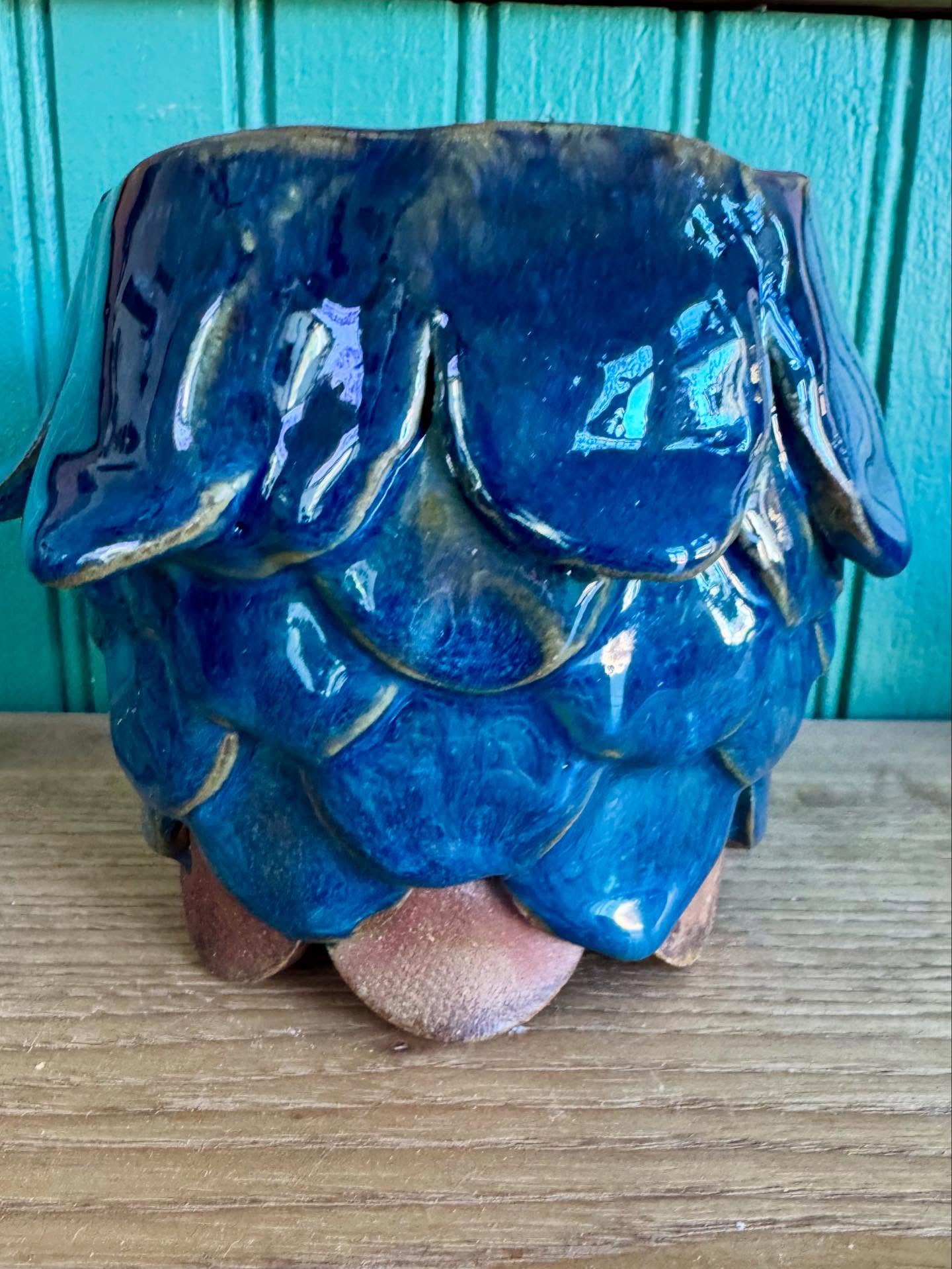 Vessel covered in overlapping glossy blue petals, with rosy unglazed tips at the base.
