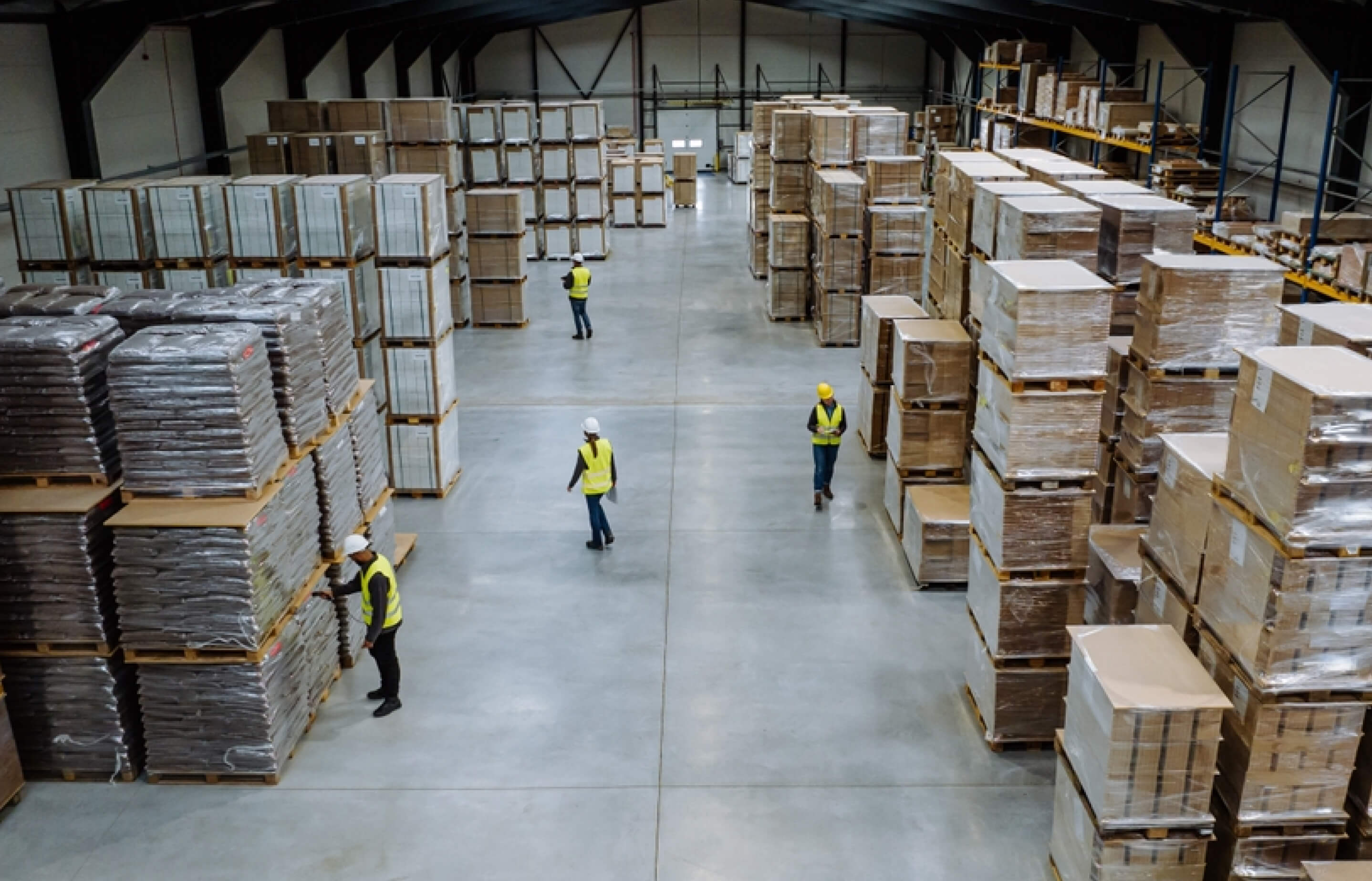 Aerial view of a warehouse filled with stacked boxes and workers moving among them.