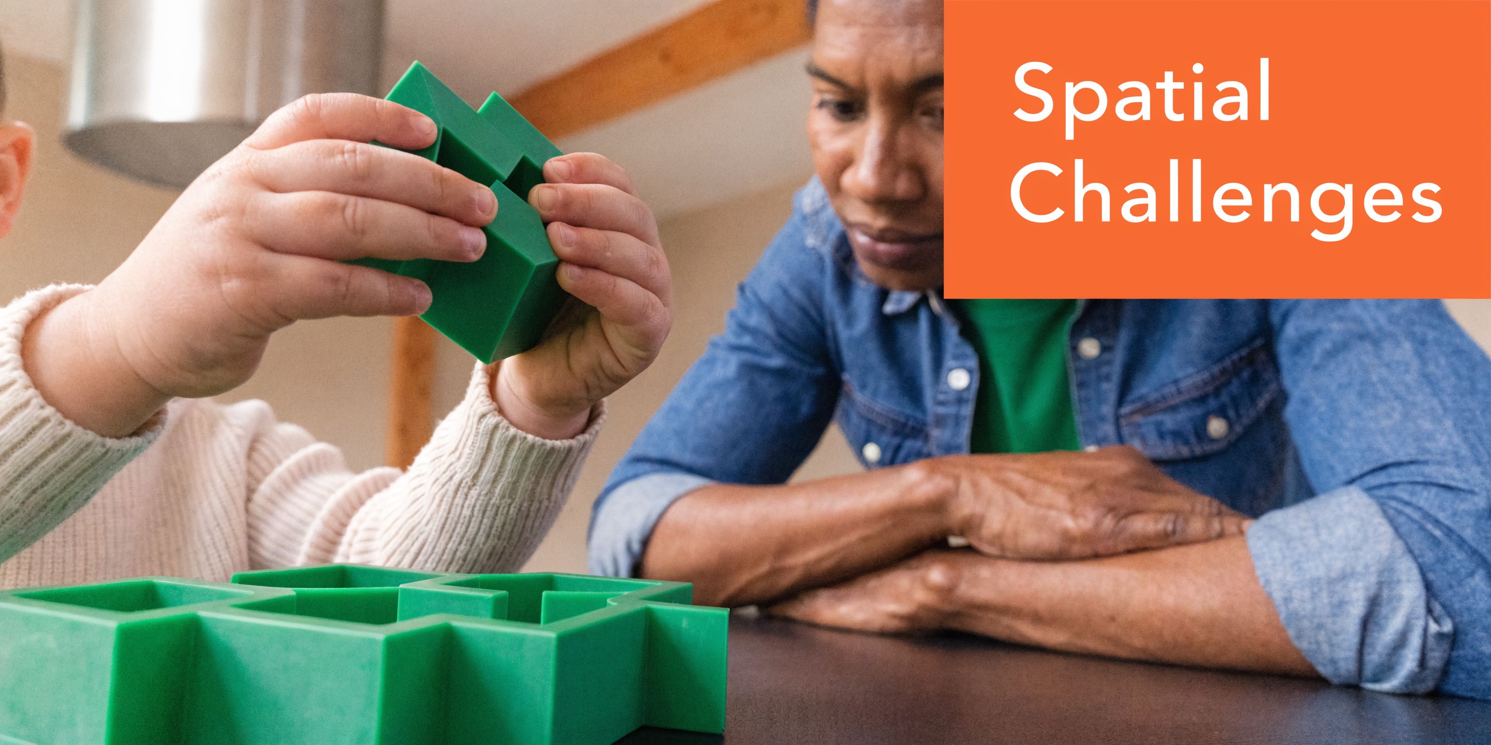 A child playing with a green block puzzle while an adult watches them closely.