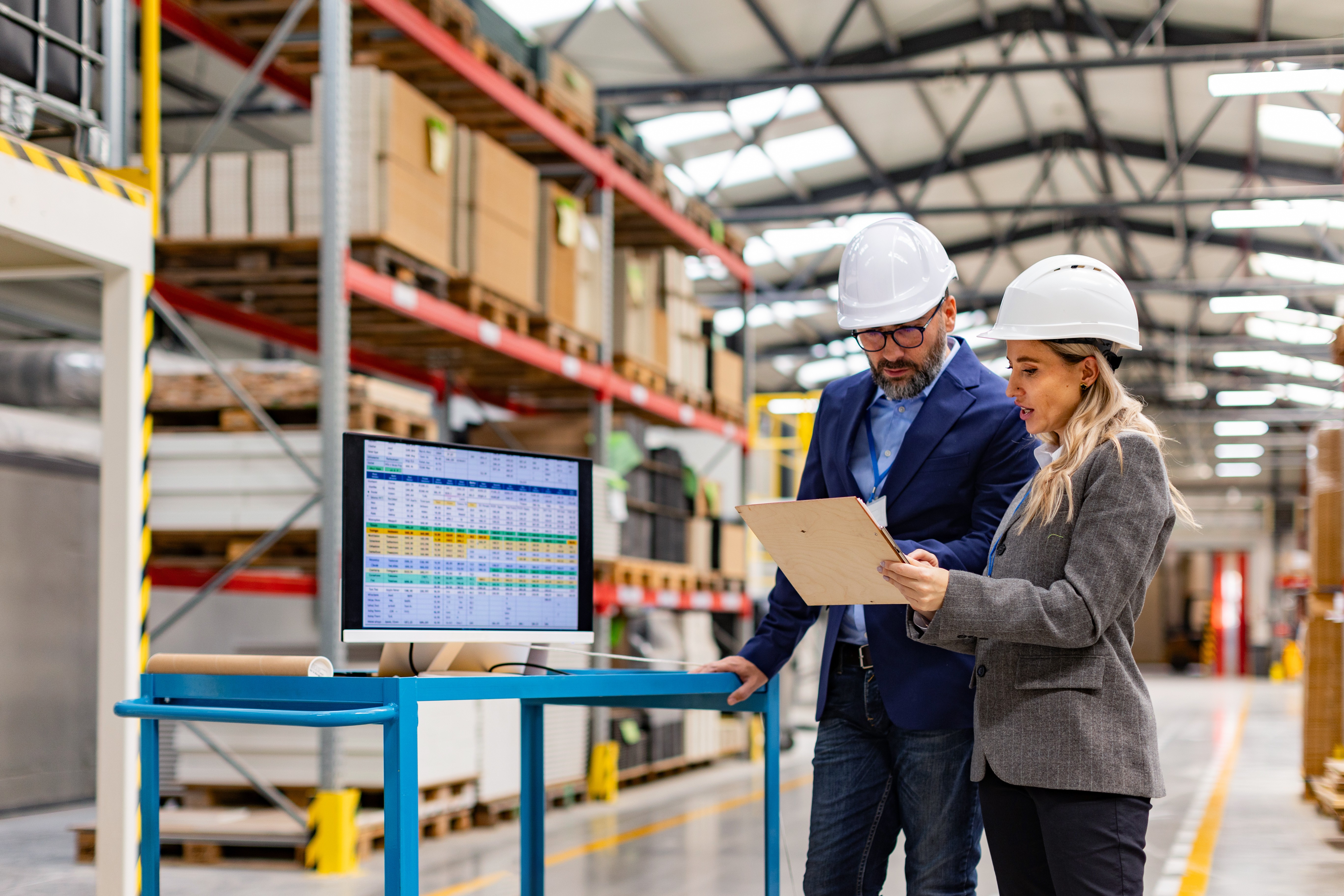 A team of workers wearing hard hats and safety vests listening to a supervisor in an industrial facility.