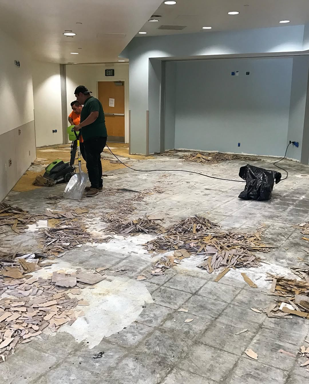 Installer scraping out old tile and adhesive during break room demolition