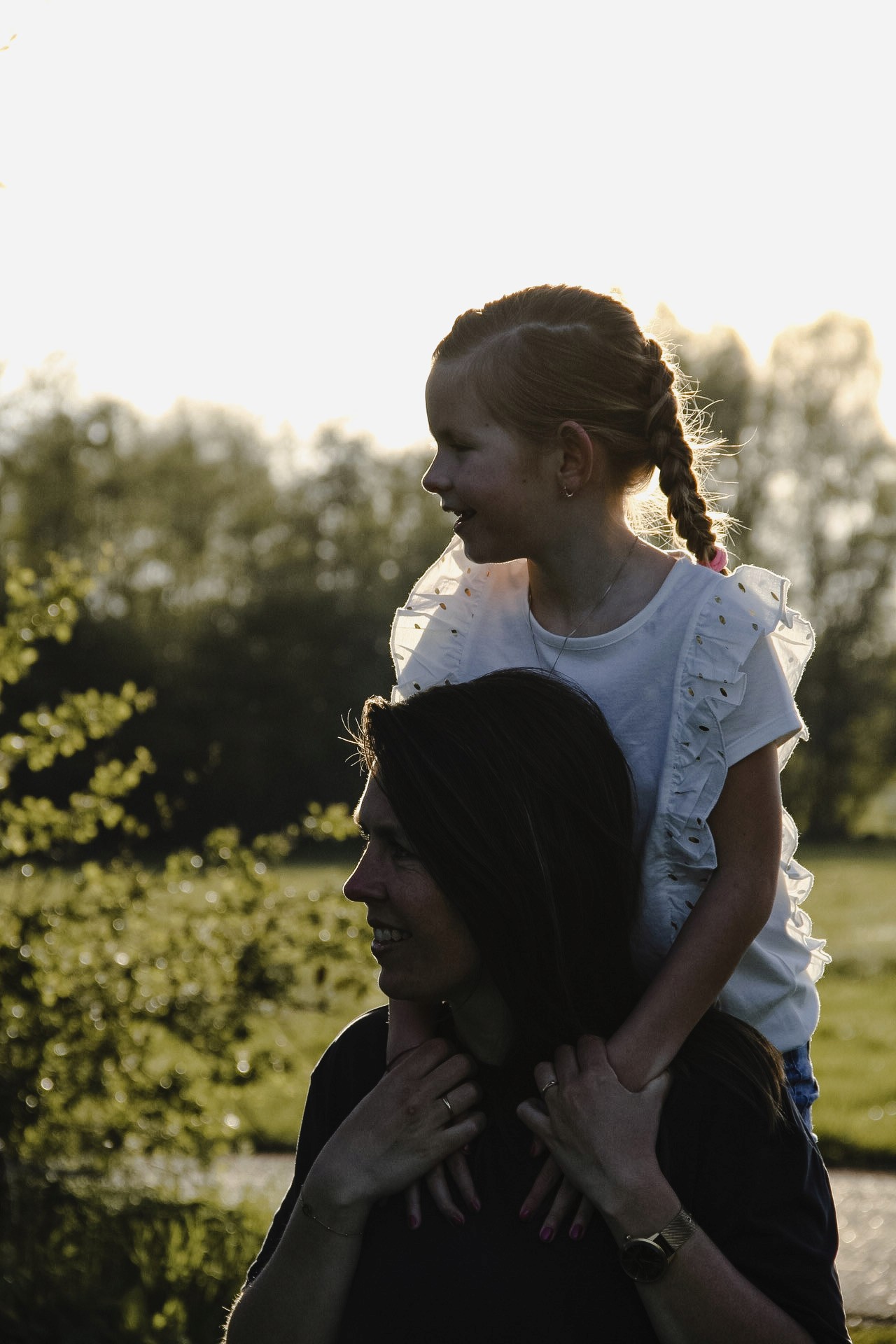 Ontroerende foto van een moeder en dochter die elkaar omarmen in het avondlicht, waarbij de warme gloed een moment van liefde en verbondenheid benadrukt