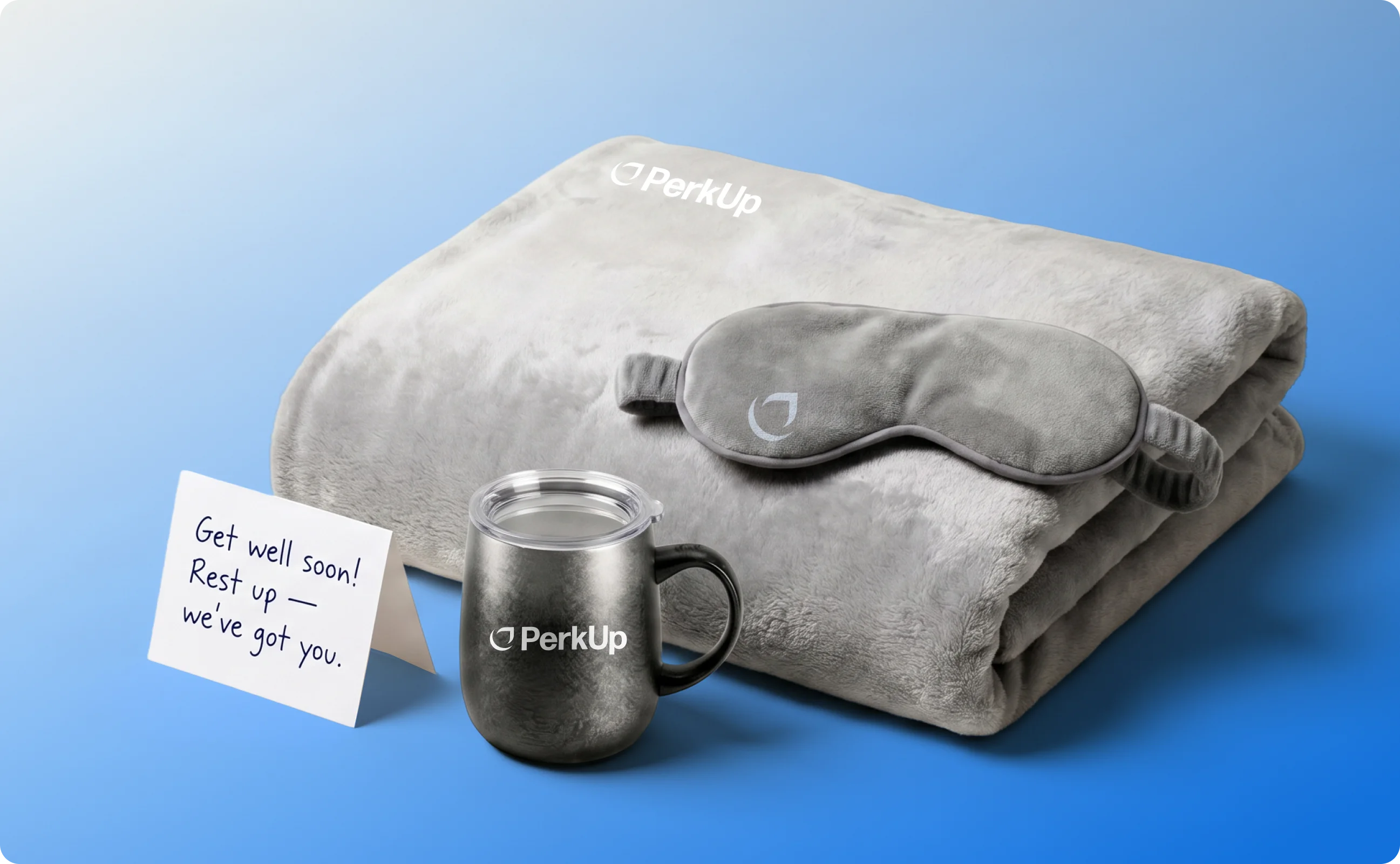 A blanket, a note, a mug, and an eye mask.
