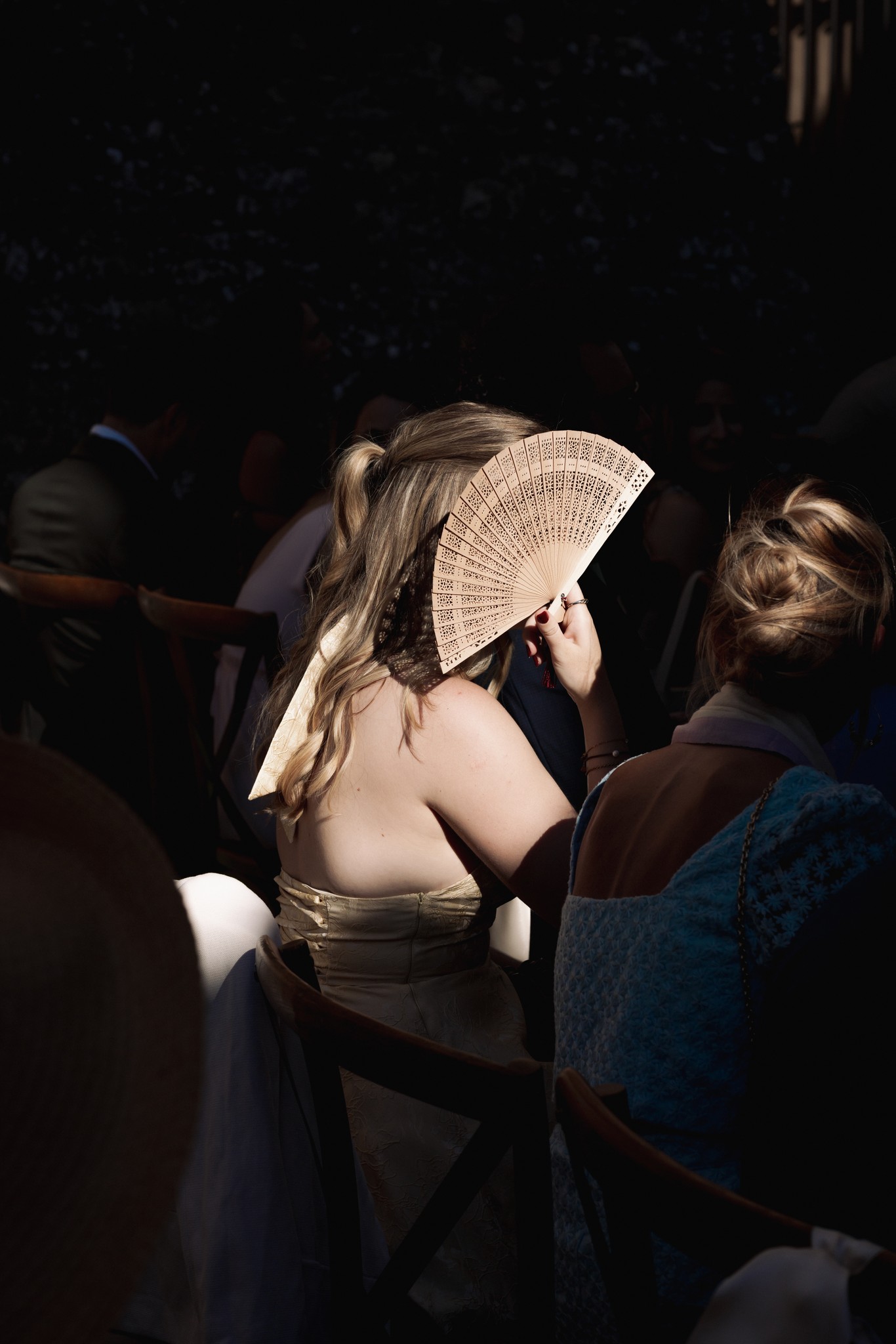Sposa con ventaglio di carta durante i preparativi al Castello di Scipione, luce naturale laterale illumina l'abito bianco