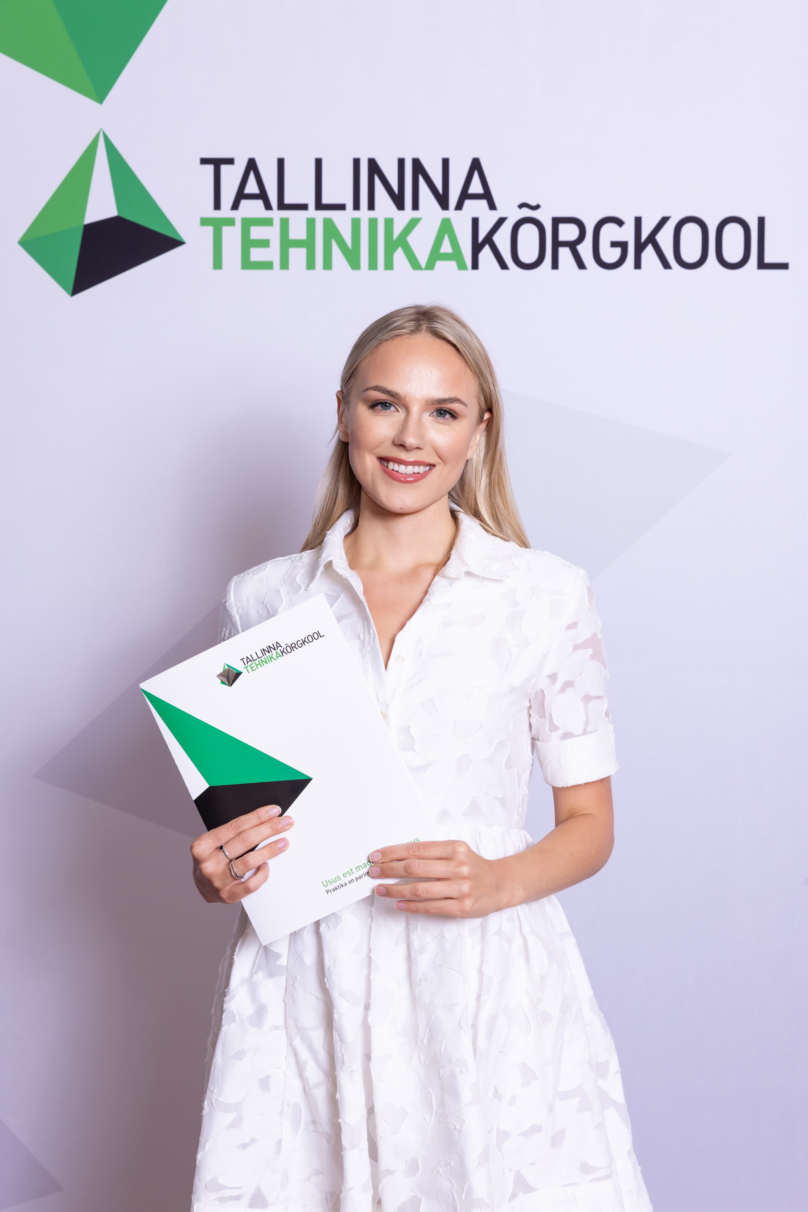 A young person with long, wavy hair sits in front of a plain background, looking directly at the camera.