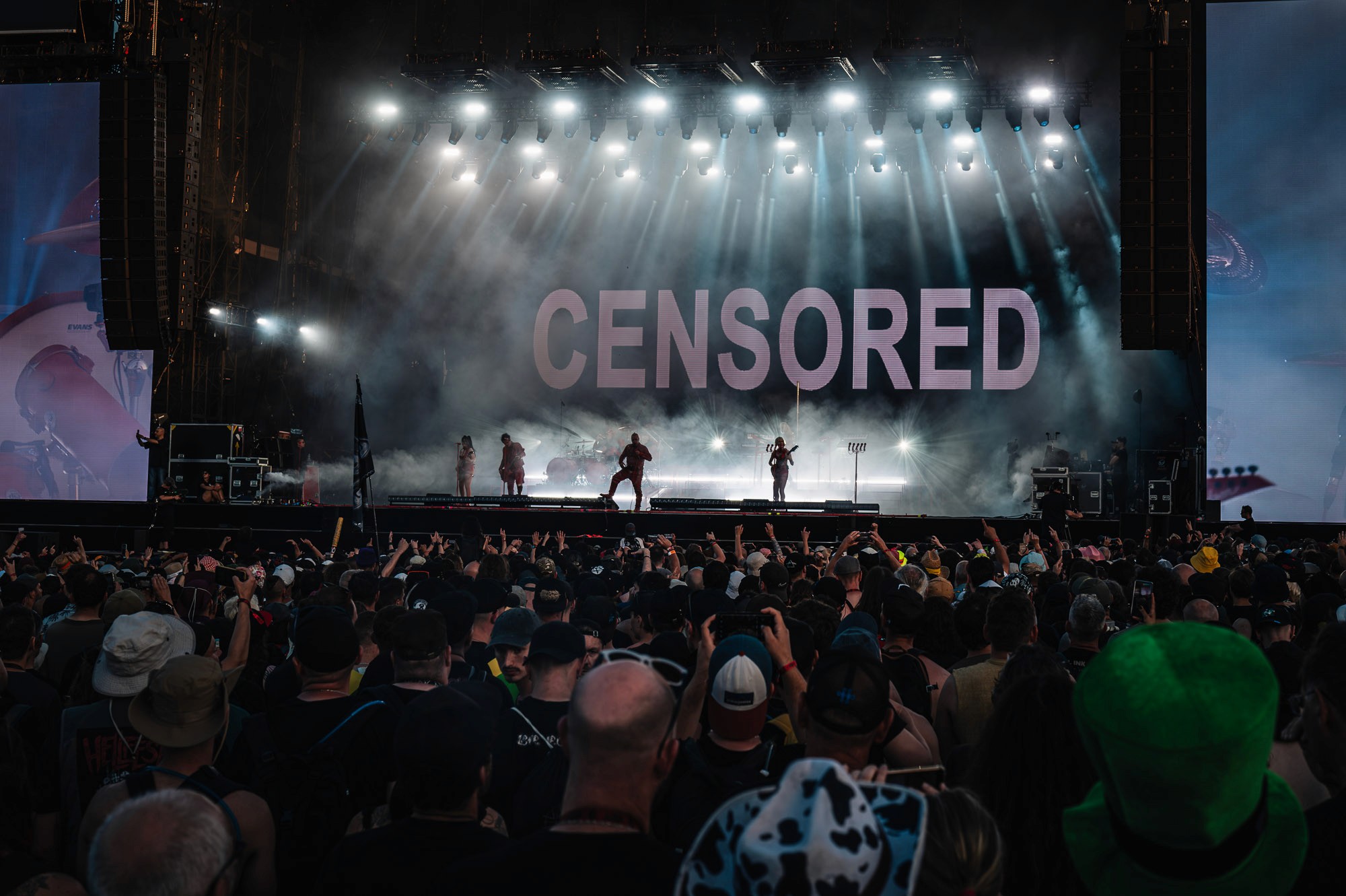 Écran géant affichant « Censored », silhouettes du groupe sur scène dans la fumée