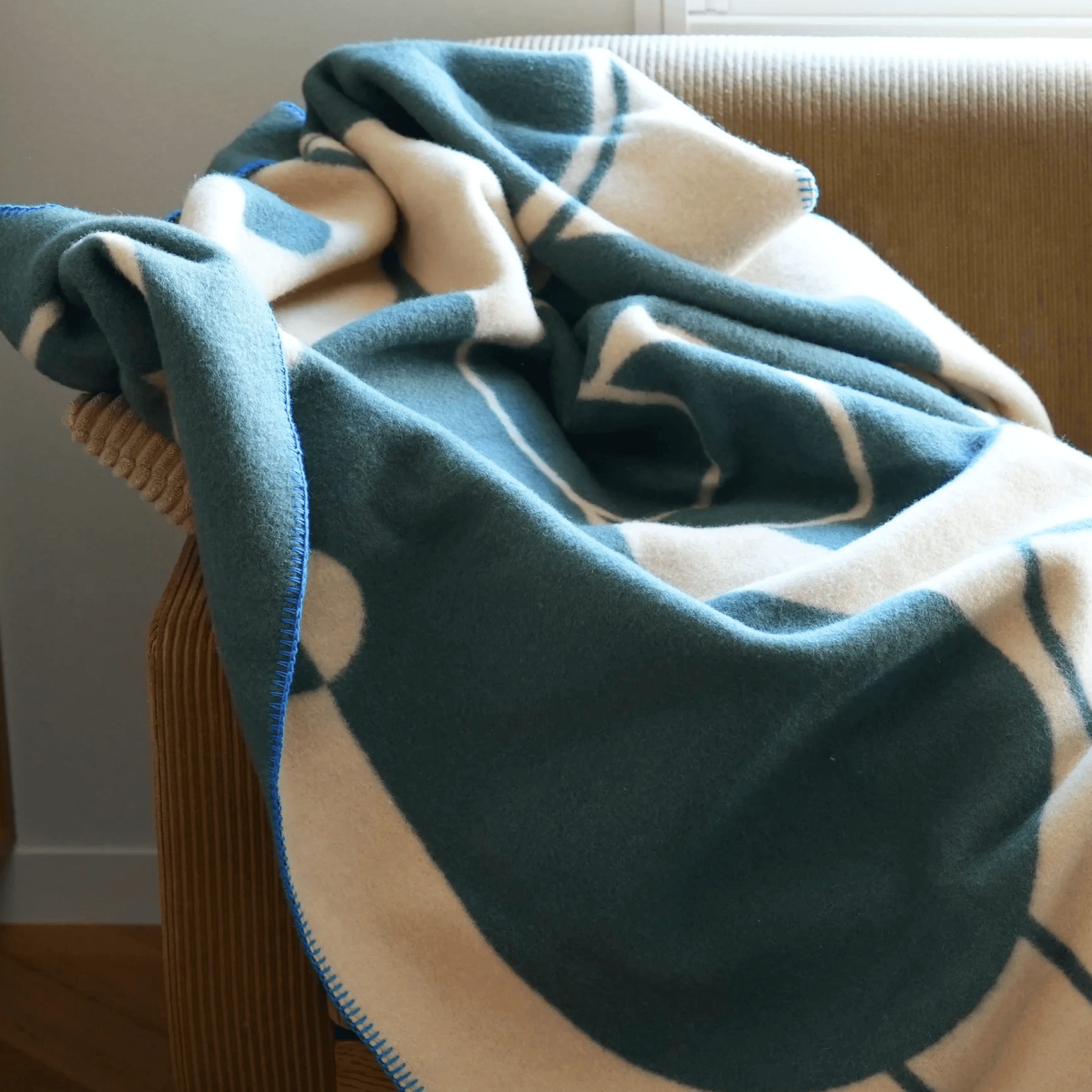 Close up of the MY TONE woven blanket showing the soft texture, graphic pattern and blue-edge finishing.