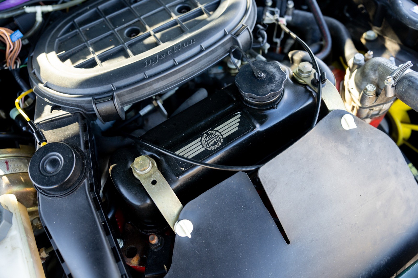 Close-up of a car engine showing various components, including wires and a sleek black cover.