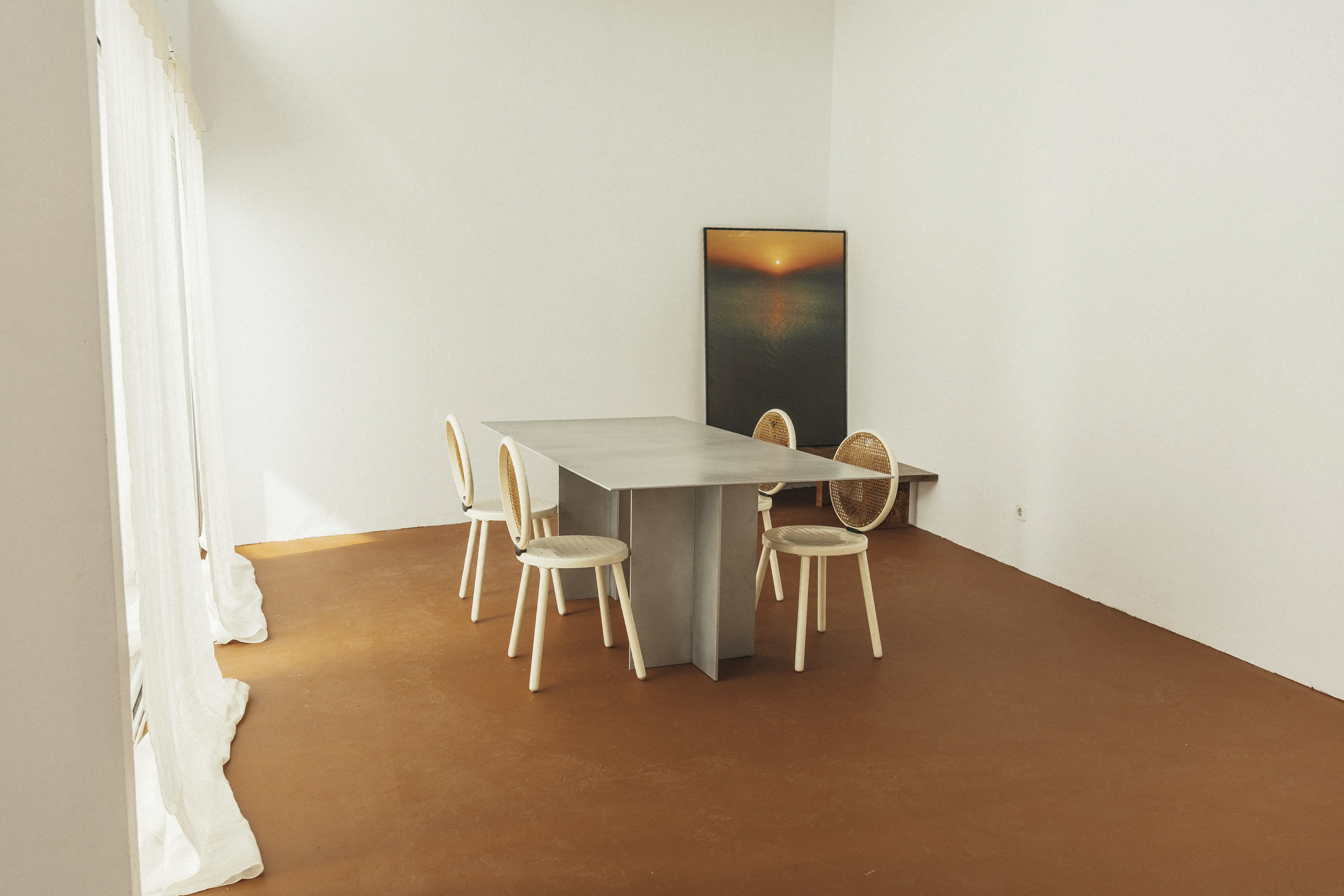 Estudio matriusca  en el que se ve una mesa de diseño con sillas en una sala con el suelo naranja.