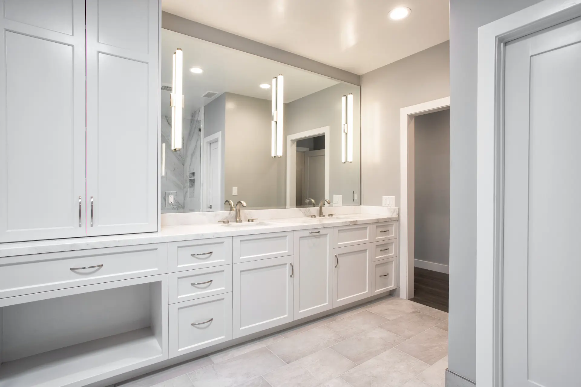 Modern kitchen with grey cabinets, central island, and recessed lighting, adjoining the living area in Costa Mesa Remodel. Photo by Chris Darnall.