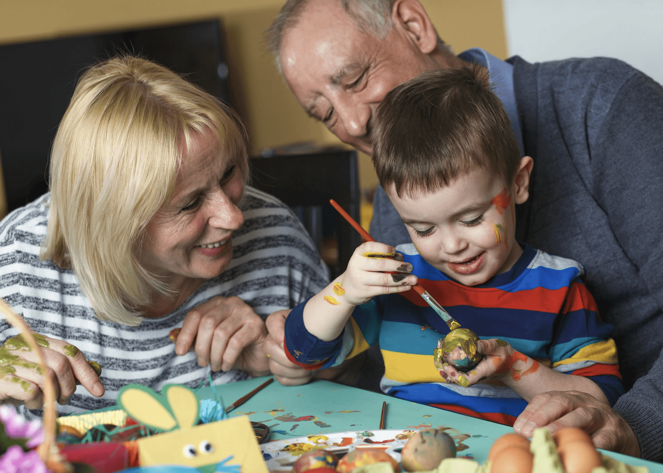 young boy paints while elderly couple watch