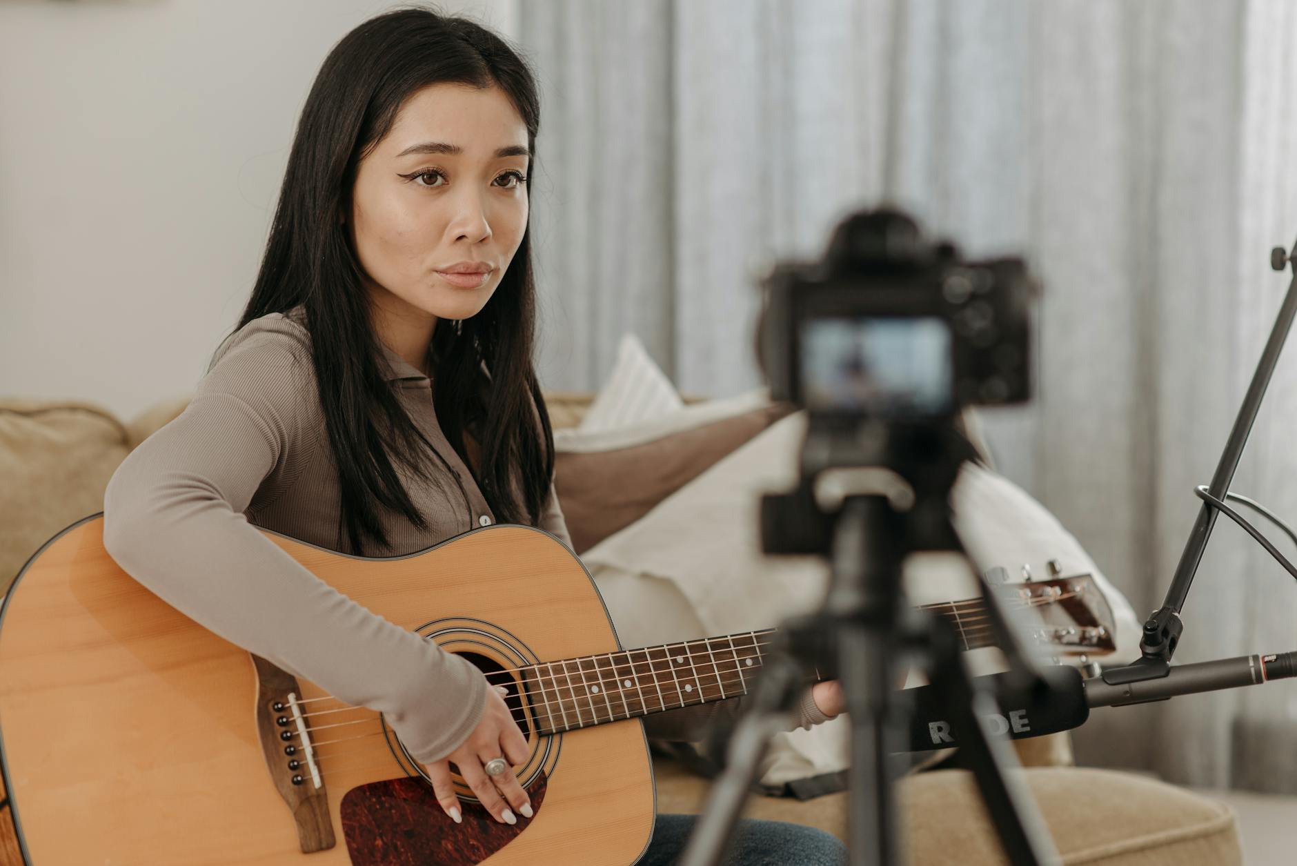A smiling educator uses a professional microphone and ring light to practice online teaching techniques.