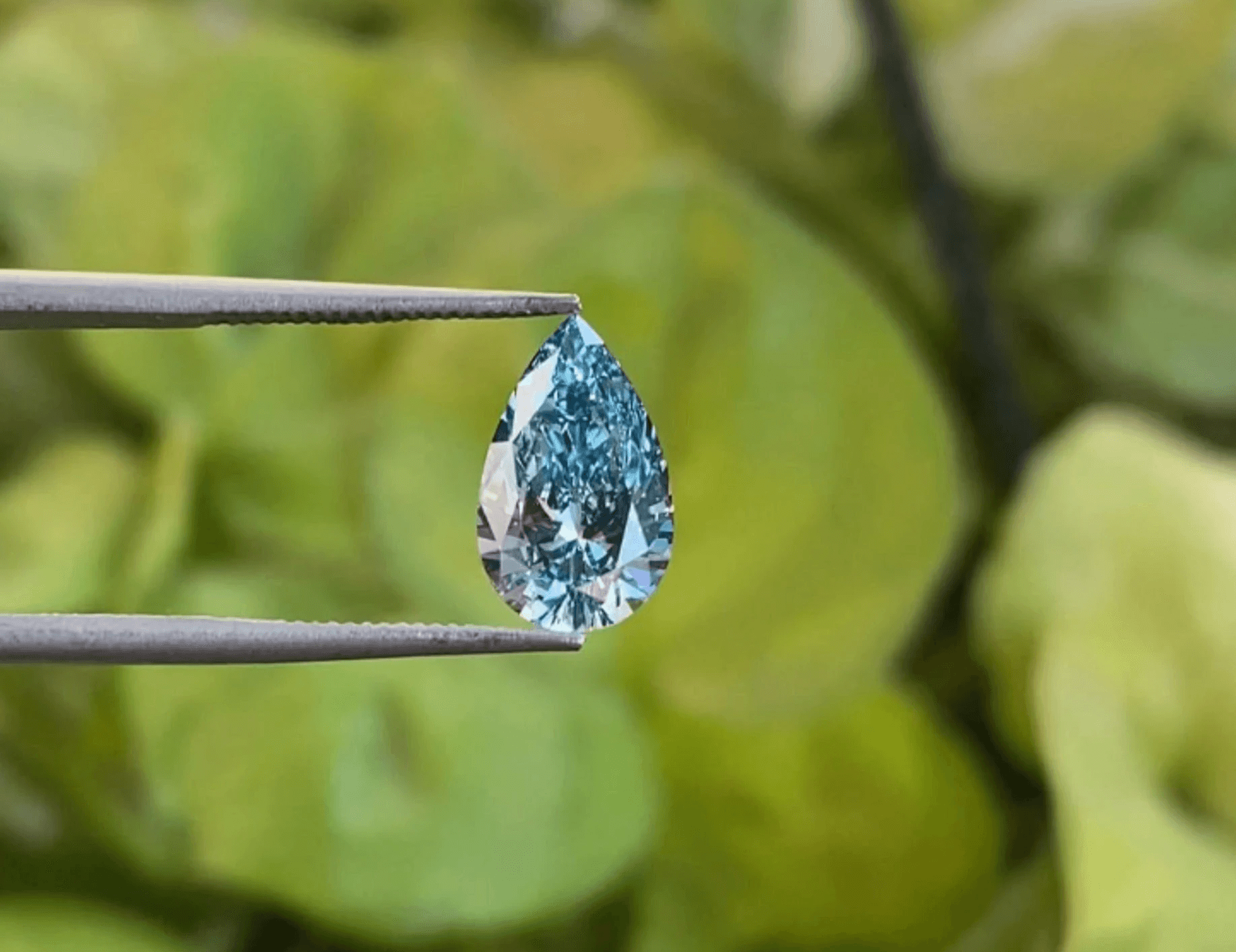 Pear shaped Lab Blue Diamond in tweezers.