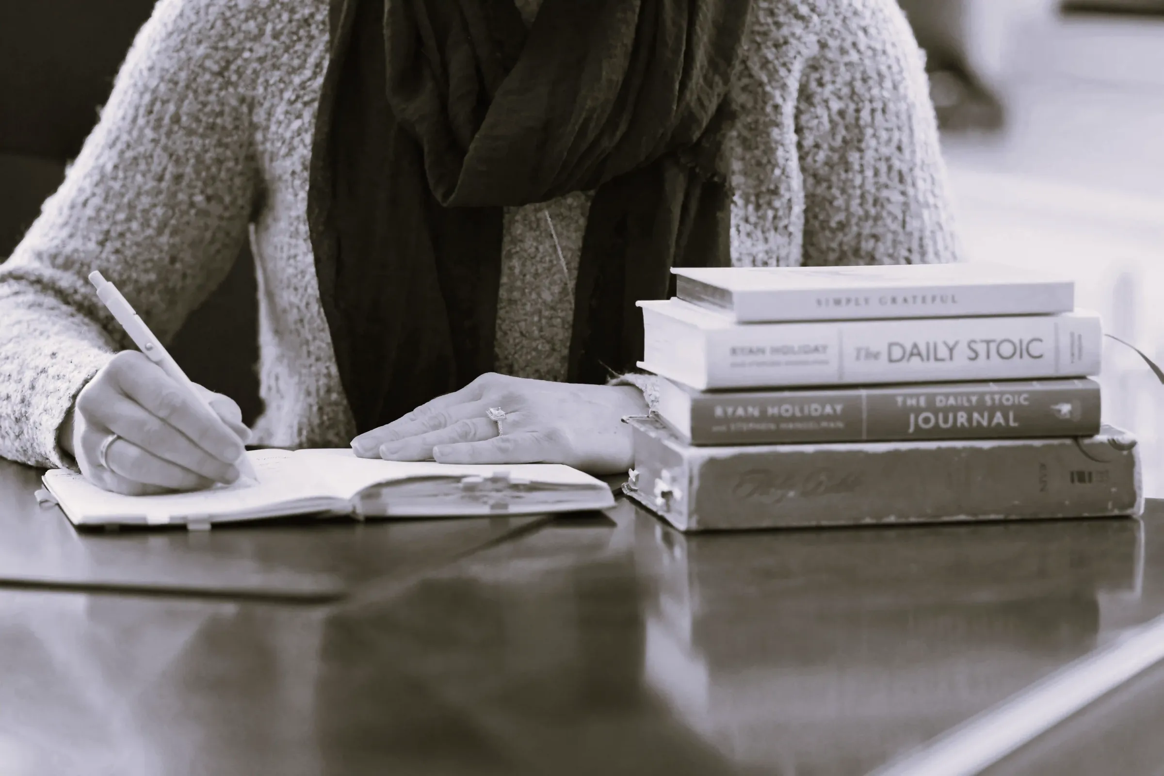 Julie writing longhand at a desk beside a stack of books