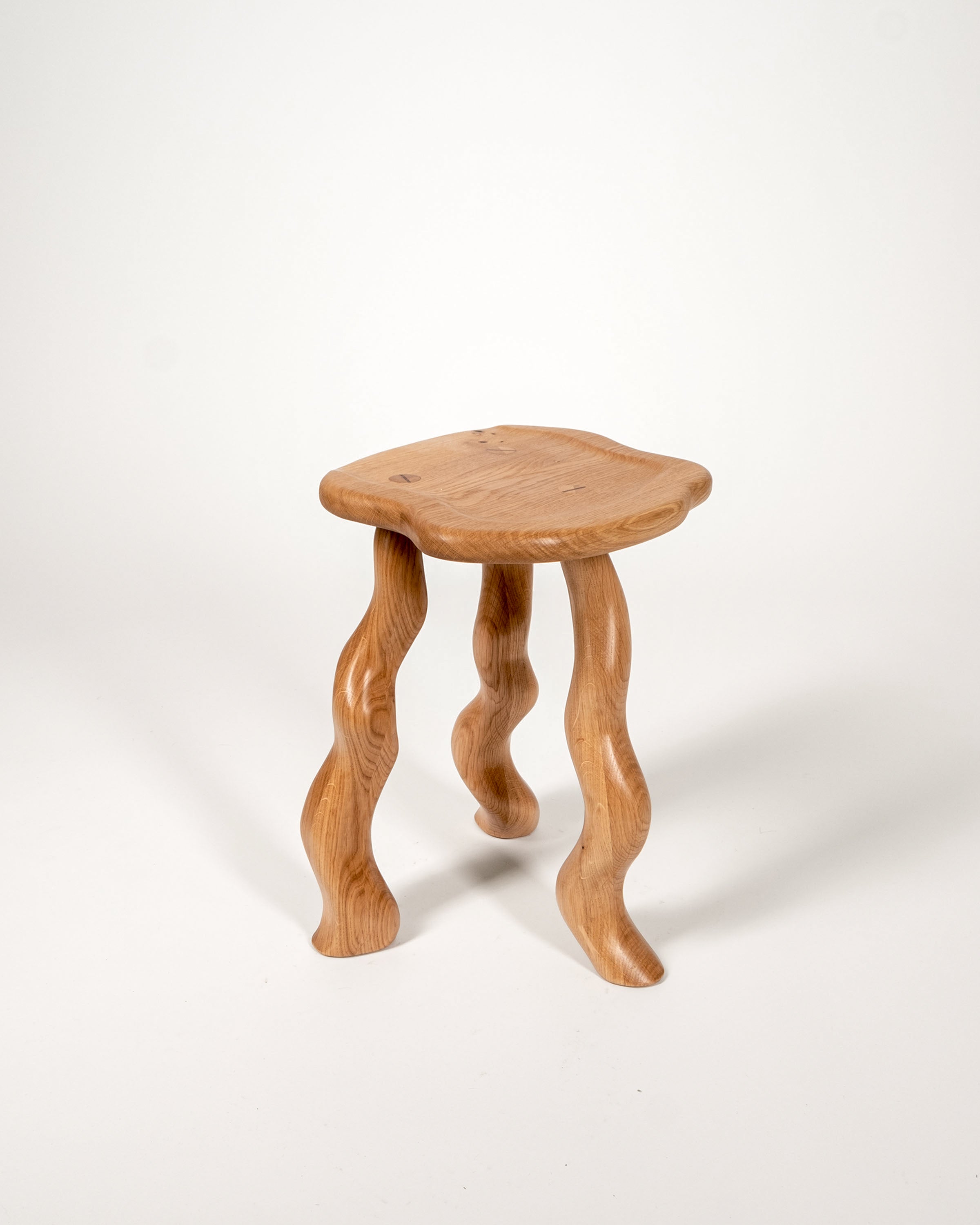 Dancing Stool in Oak with carved wavy legs by Wilkinson & Rivera.