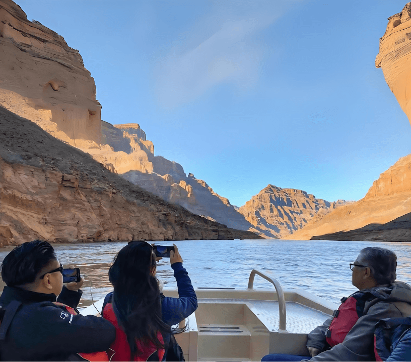 3 people are relaxing on a serene pontoon boat ride along the Colorado River.