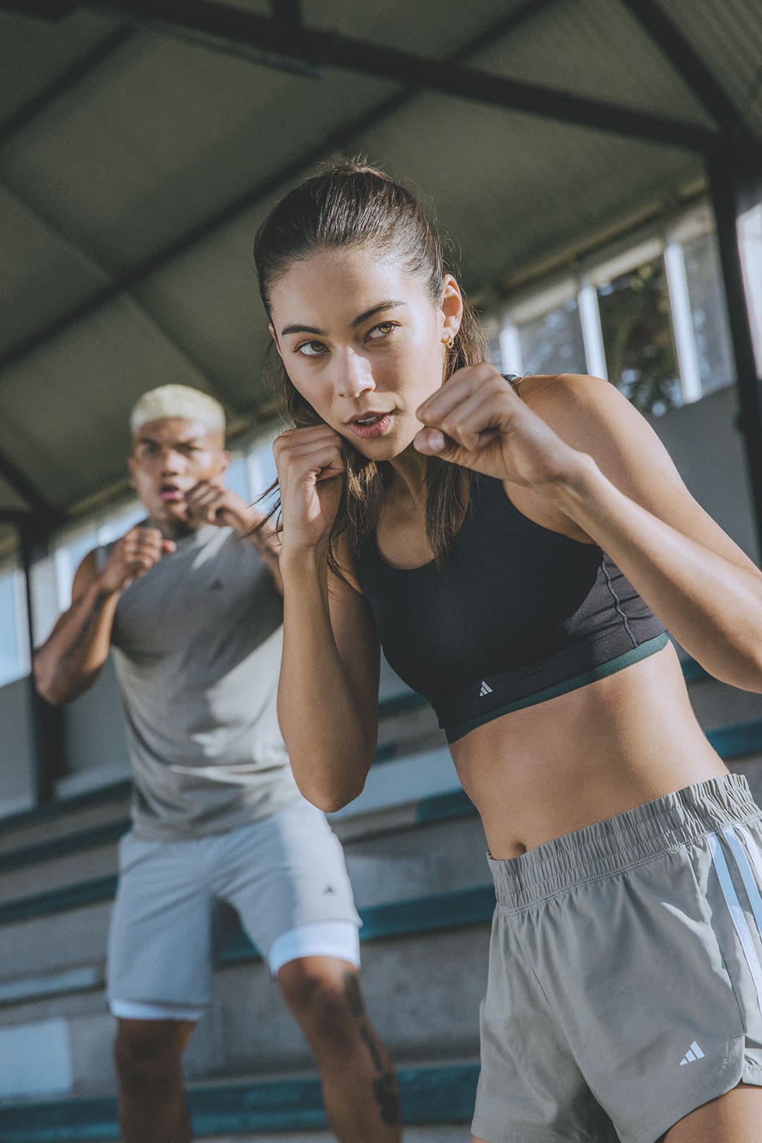 Eine Frau und ein Mann stehen schlagbereit da, während eines Bodycombat-Workouts aus.