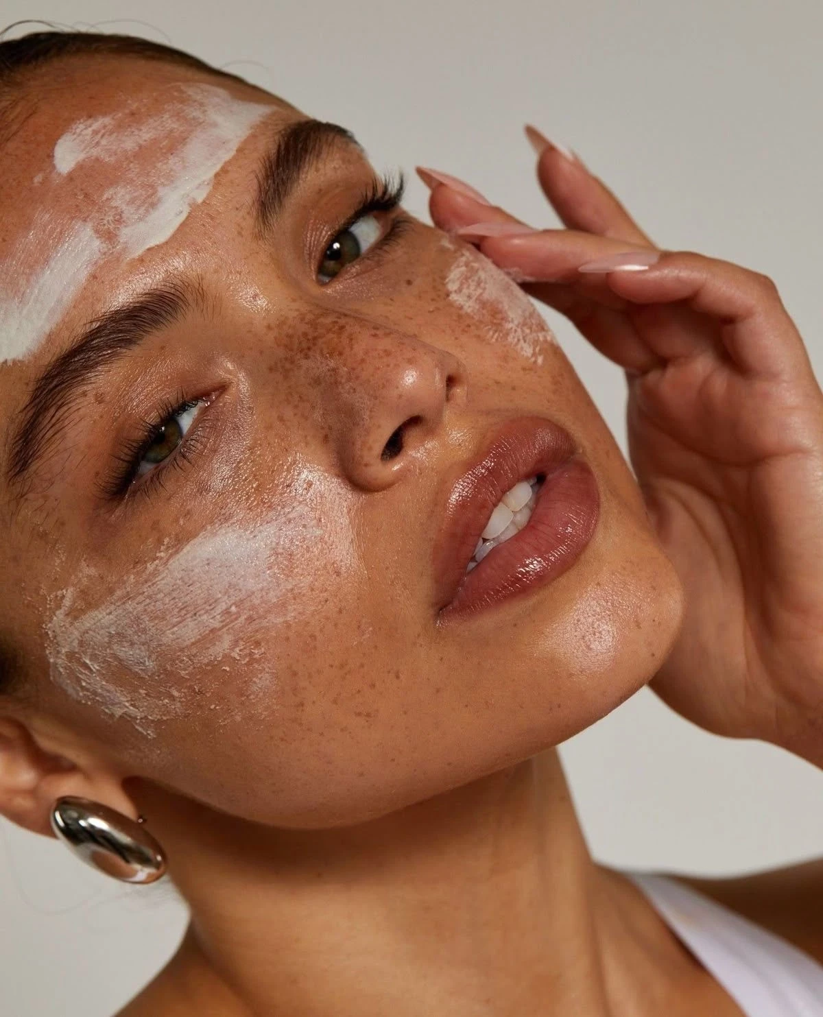 Model applying face cleanser scrub during skincare routine