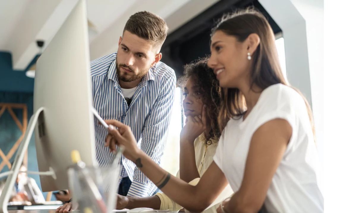 2 ladies and 1 man looking at a computer in their white office