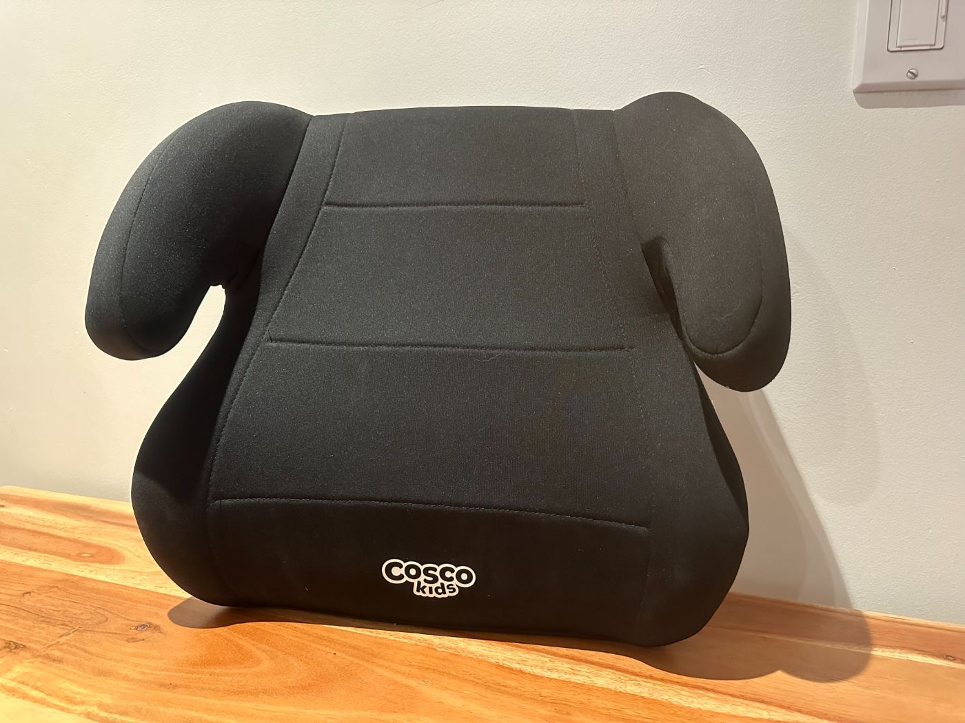 Siège d’appoint pour enfant Cosco Kids noir, posé sur une table en bois